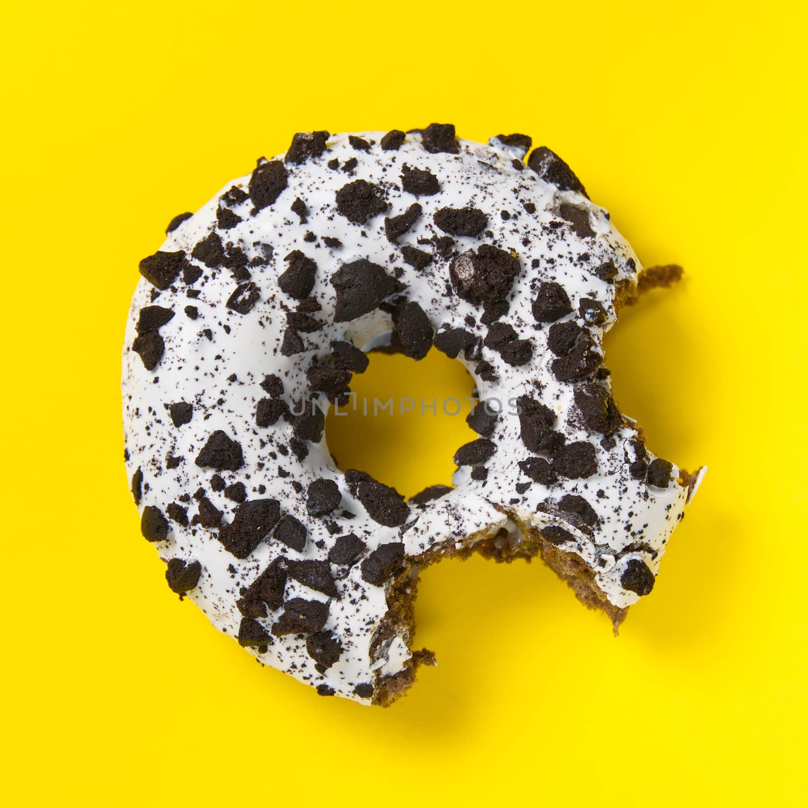 chocolate donut with white glaze isolated on yellow background, close up flat lay