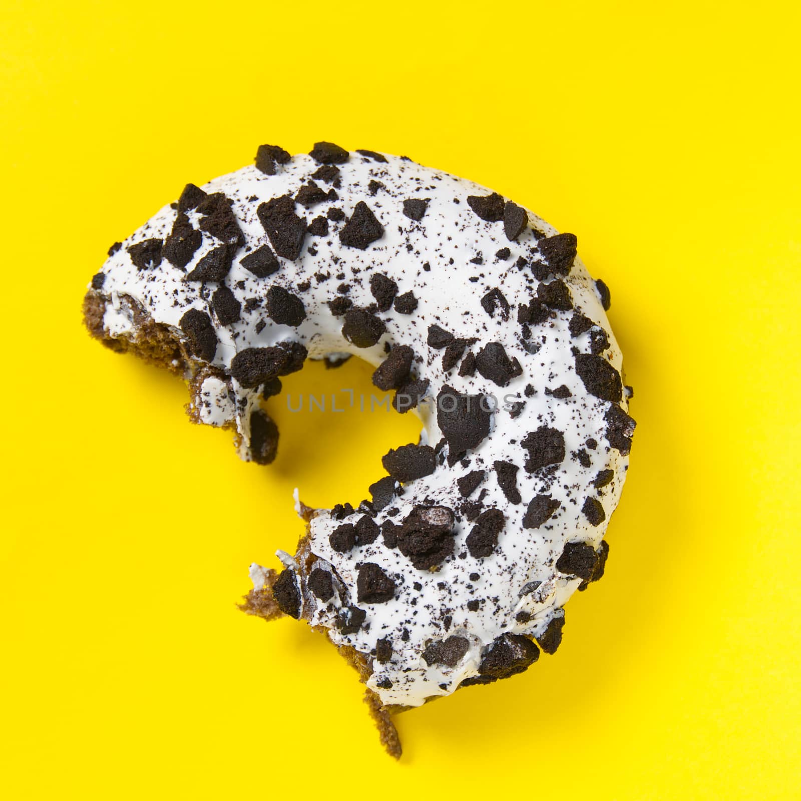 chocolate donut with white glaze isolated on yellow background, close up flat lay