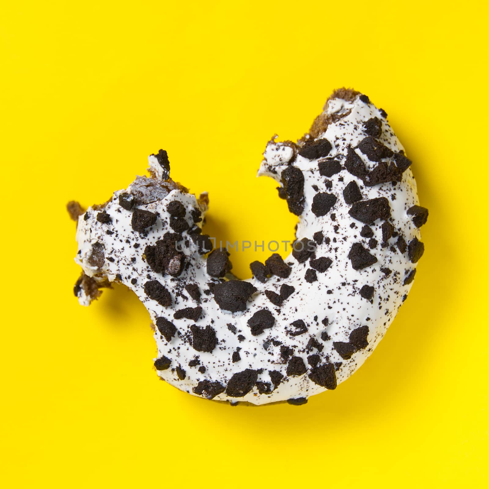 chocolate donut with white glaze isolated on yellow background, close up flat lay