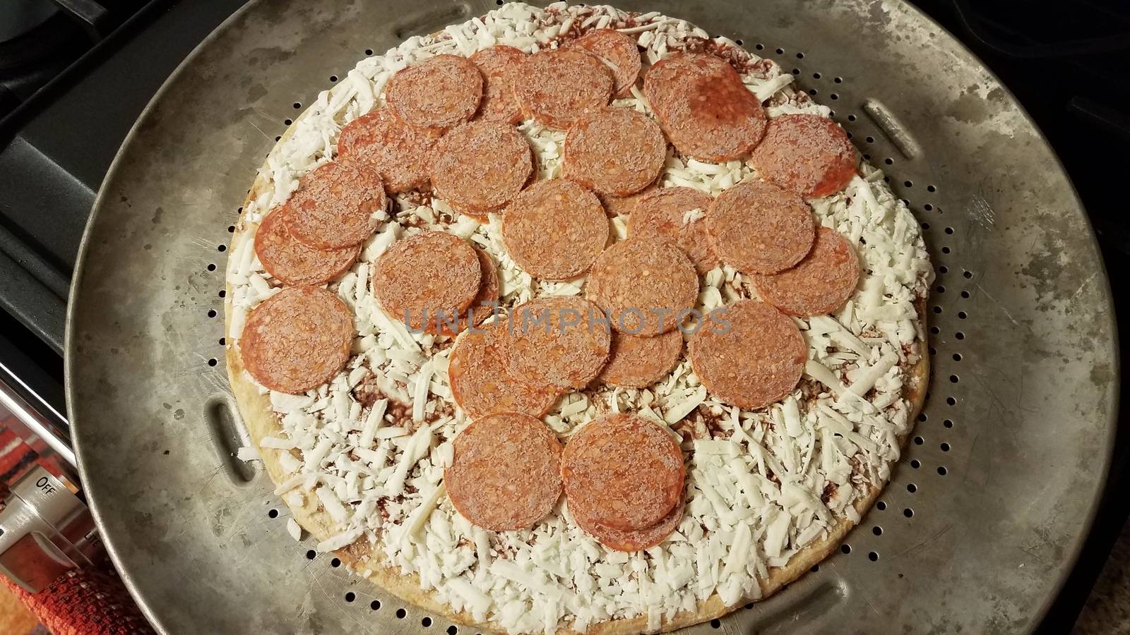 frozen pepperoni meat slices on pizza on metal baking tray