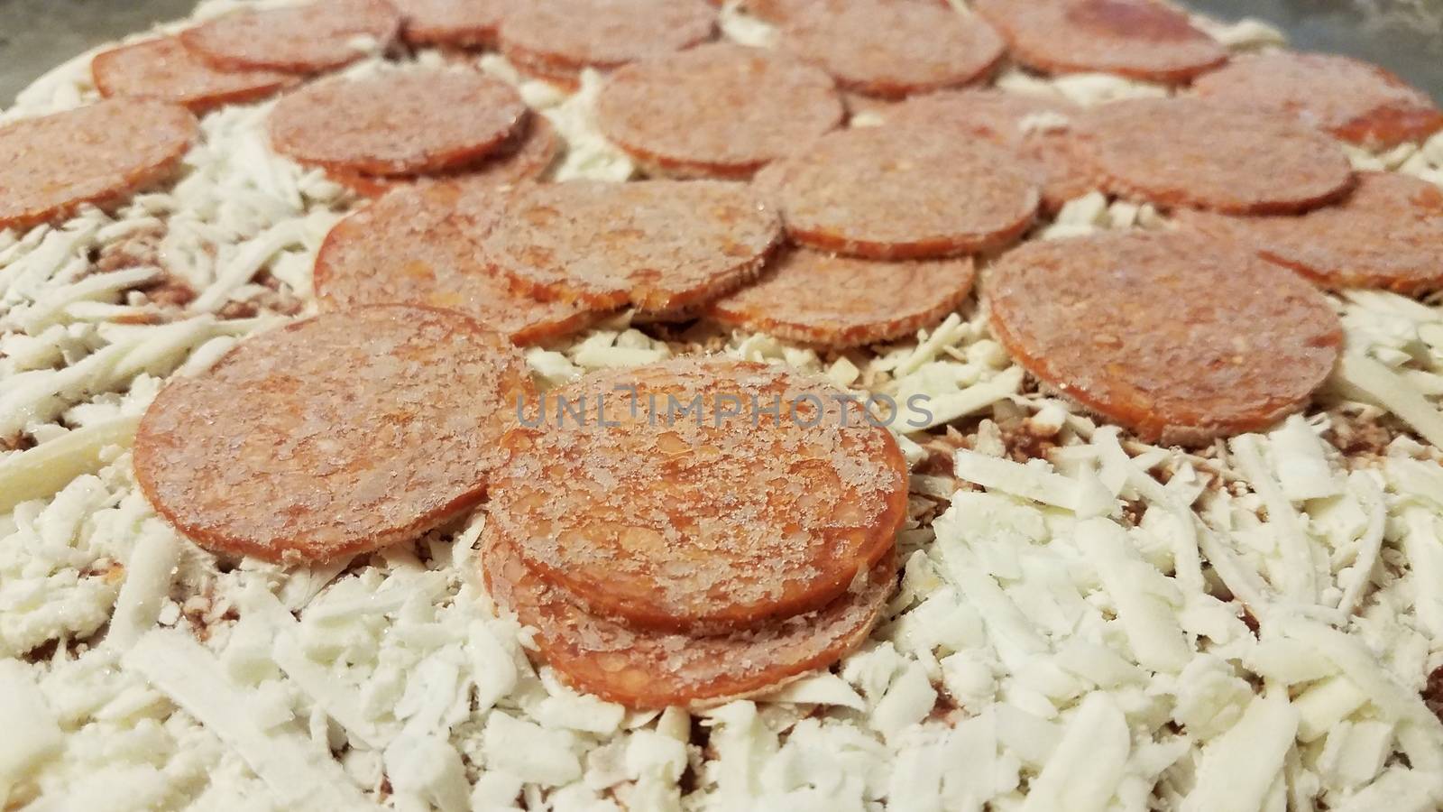 frozen pepperoni meat slices on pizza on metal baking tray