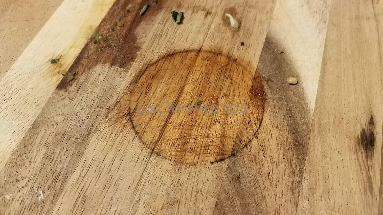 dirty wood cutting board with bits of food and circular stain