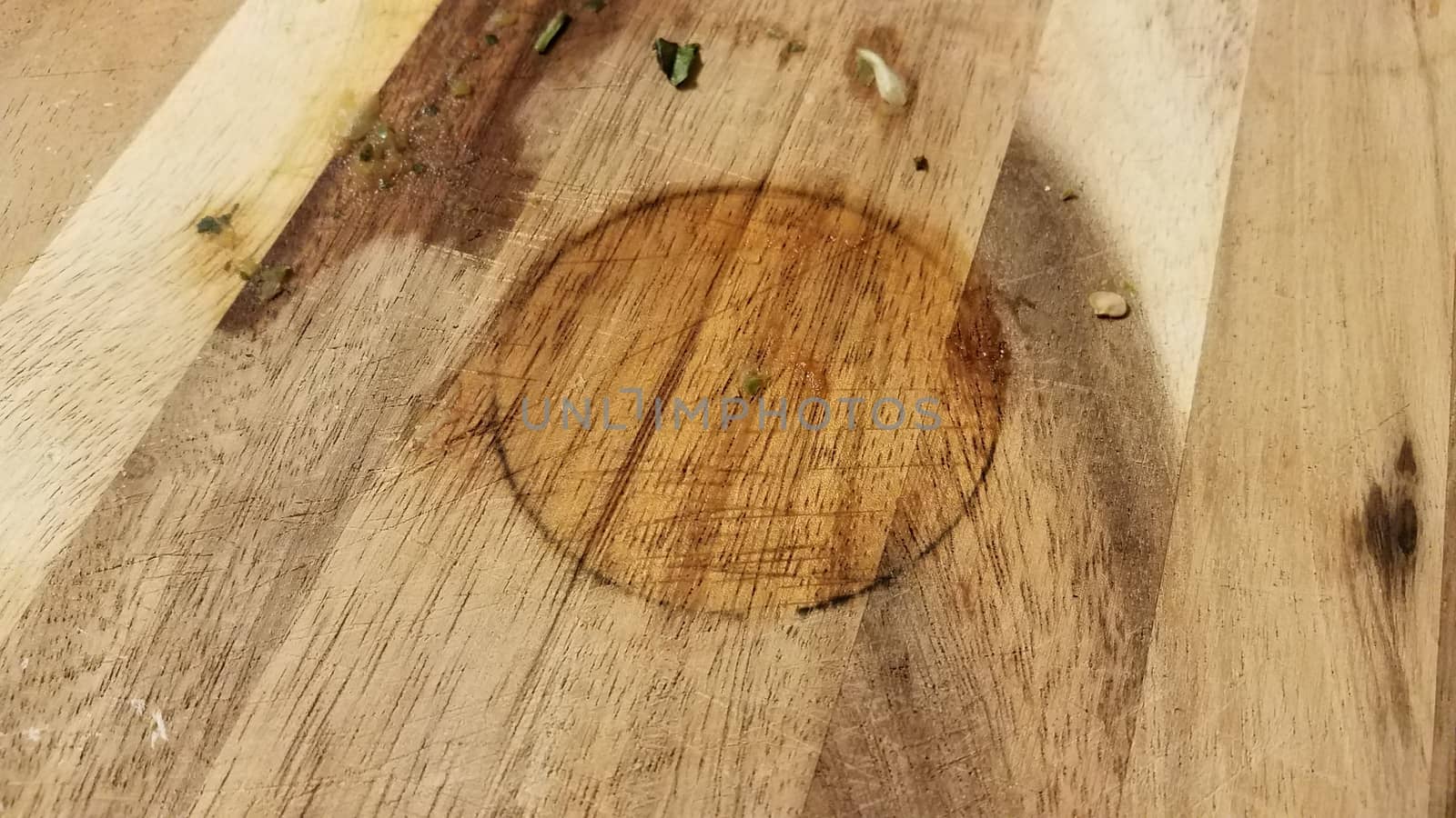 dirty wood cutting board with bits of food and circular stain
