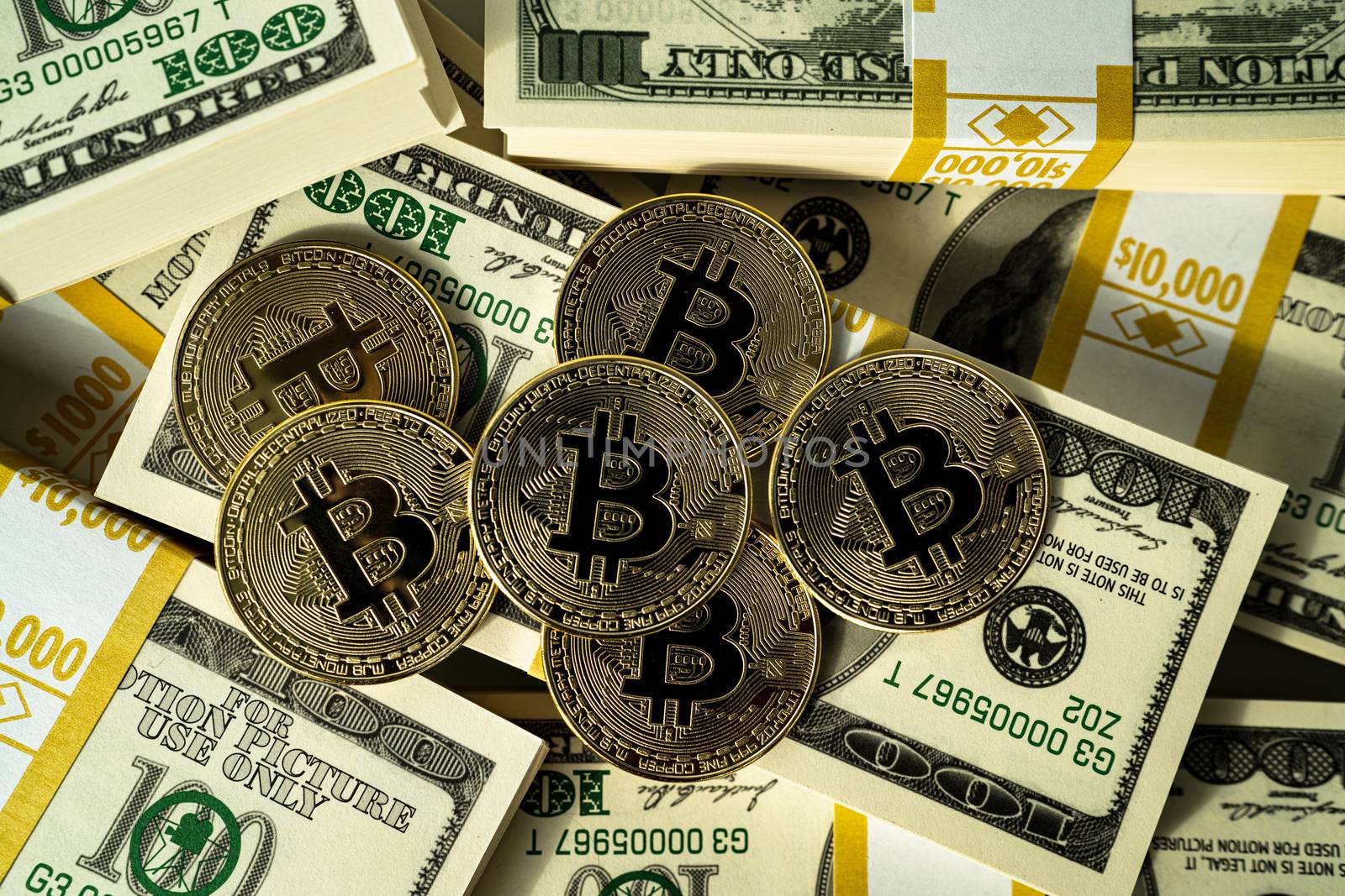 Bitcoin cryptocurrency and US dollars cash - photo of golden bitcoins physical gold coins on us dollars. Making money with bitcoin.
