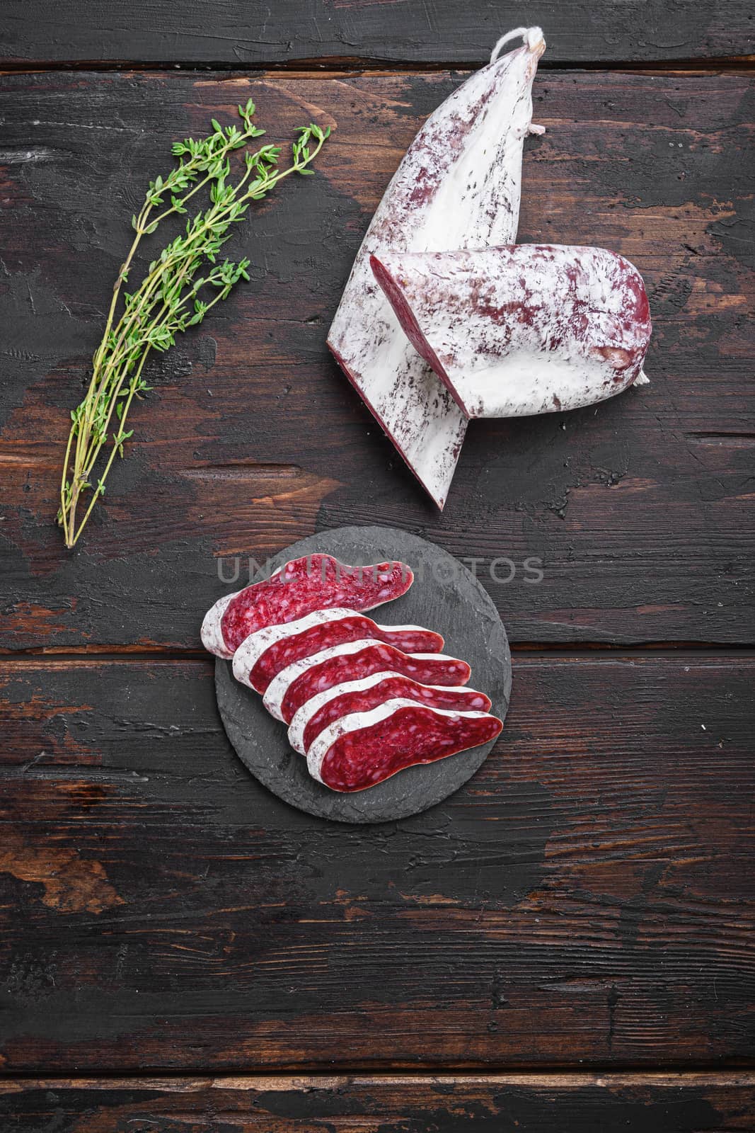 Longaniza, dry cured traditional sausage cut to slices on old wooden table, flat lay with copy space.