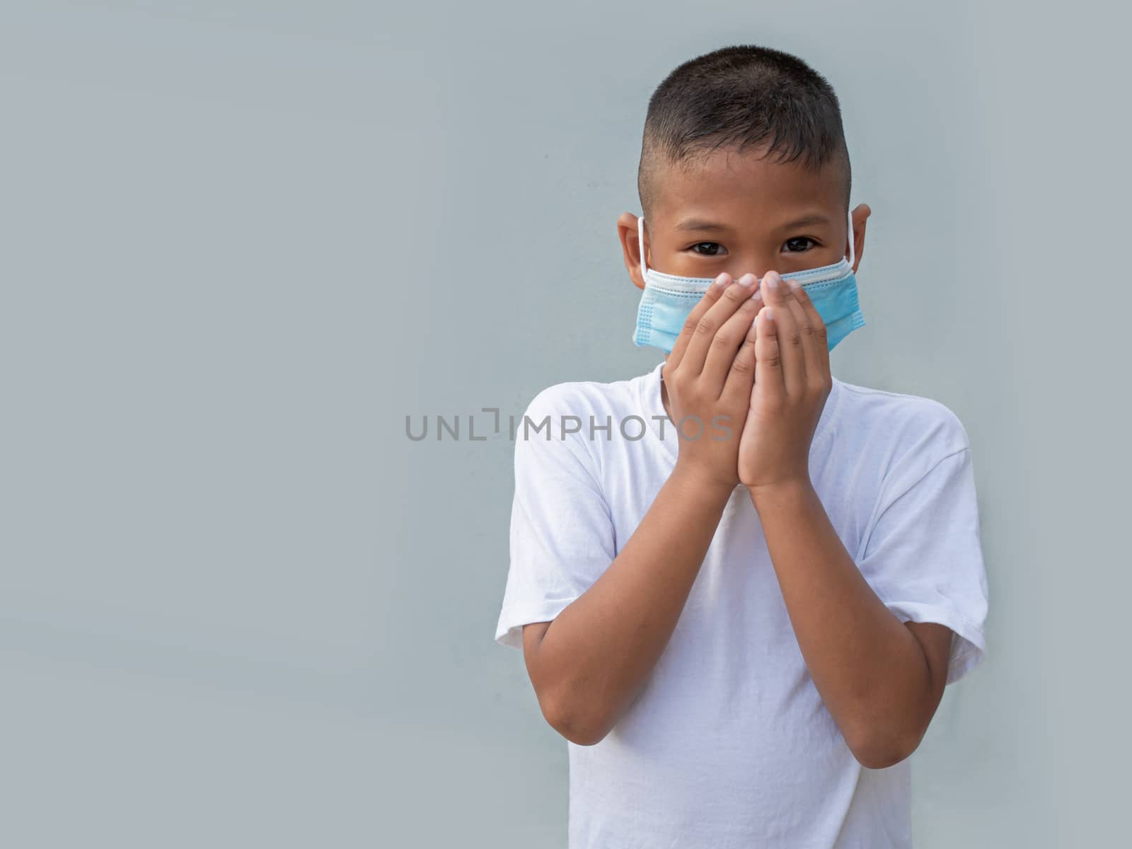 Boy wearing a protective mask And put his hand on his mouth On a gray background. New normal concept.