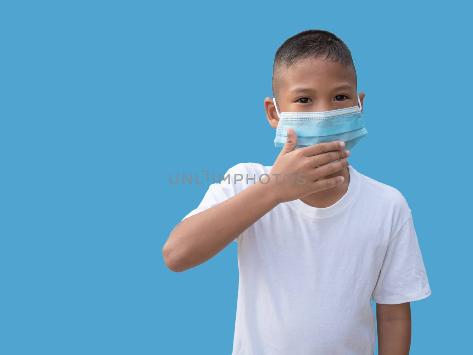 Boy wearing a protective mask And put his hand on his mouth On a blue background. new normal concept. by Unimages2527