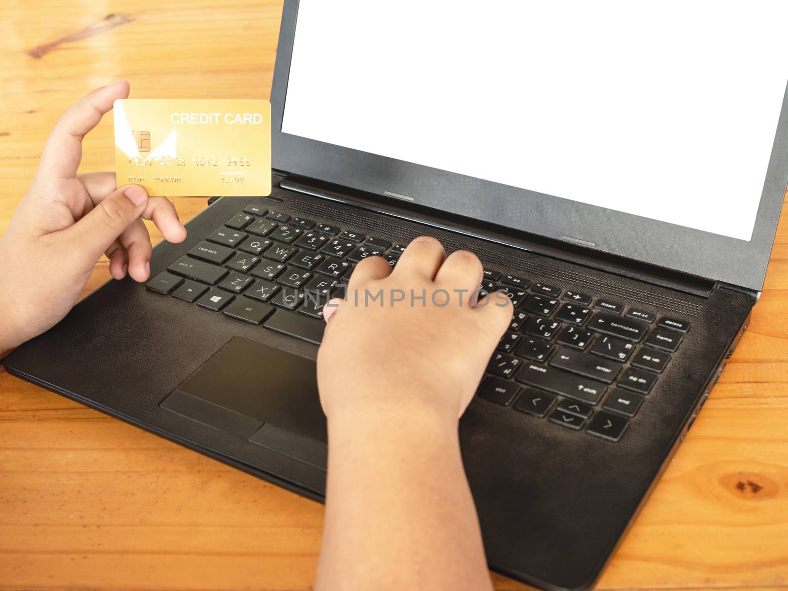 Close-up human hands holding a credit card and using computer. online shopping concept. by Unimages2527