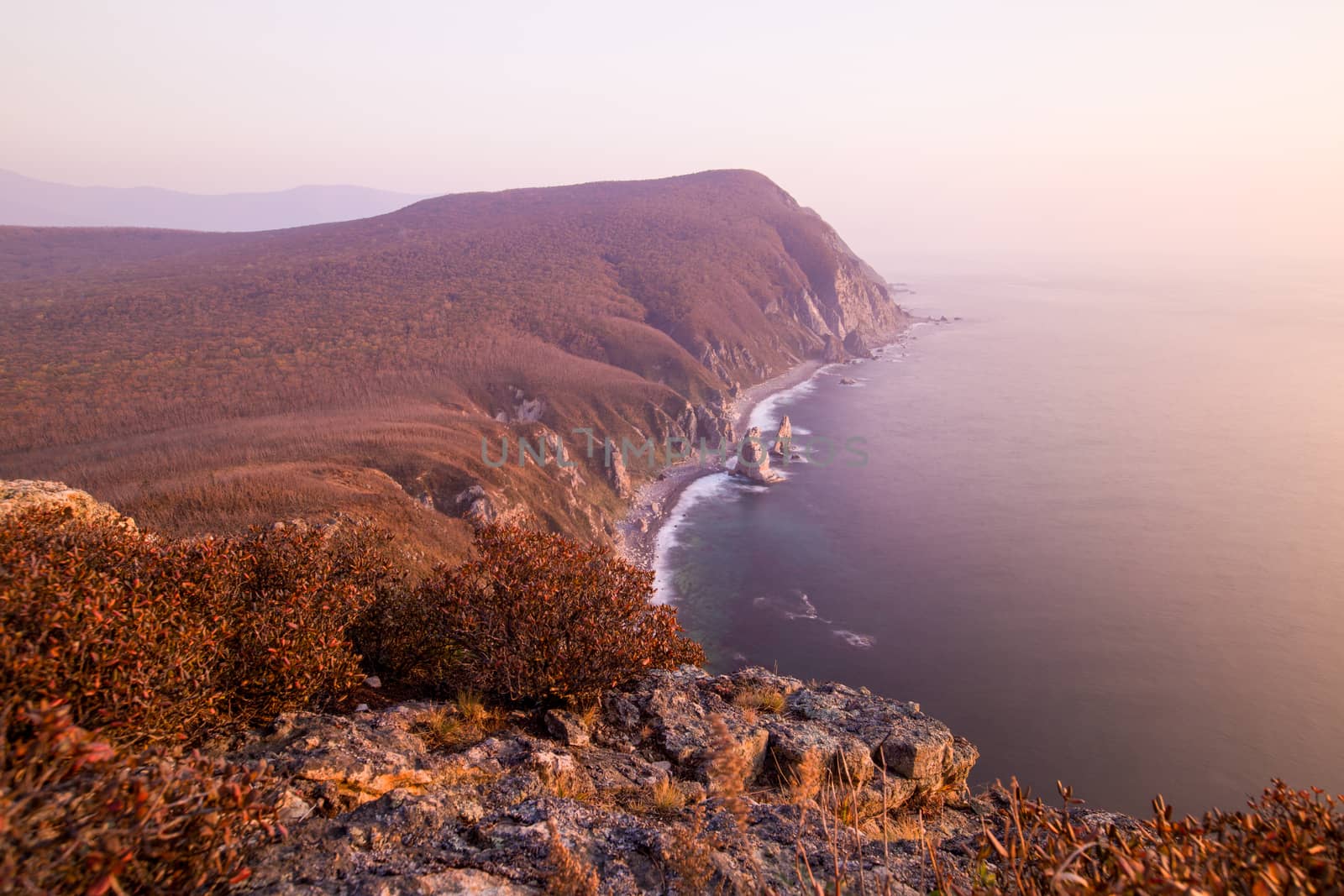 Panoramic view of the rocky coastline of the nature reserve during pink sunrise