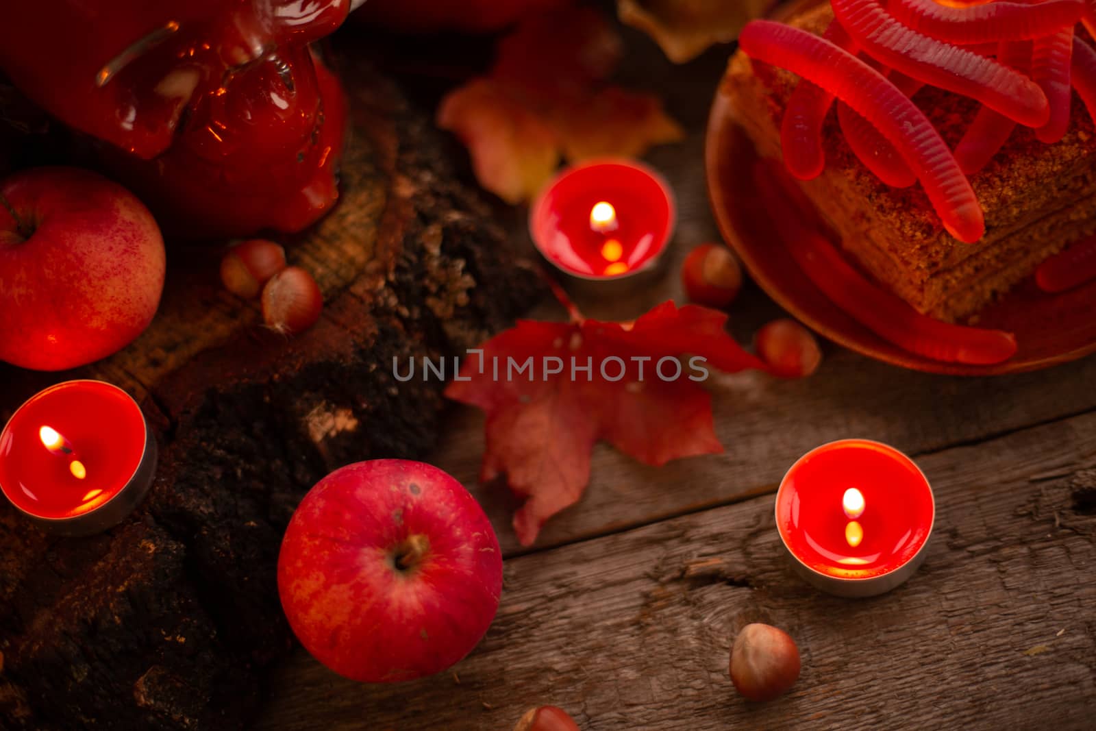 Halloween food still life abstract background with pumpkins, apples, cake, gummy worms, skull red drink and candles