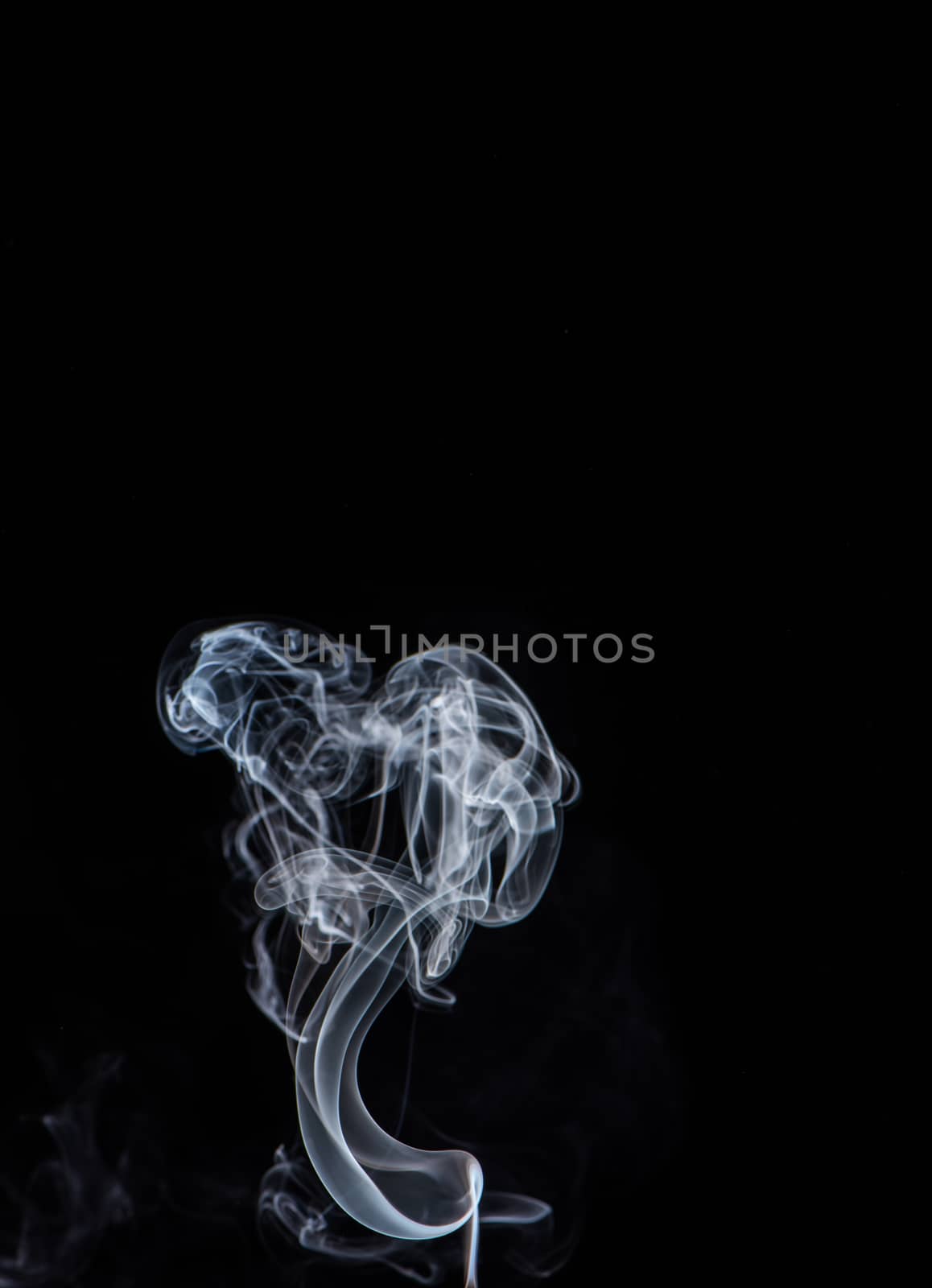 Conceptual image of white color smoke isolated on dark black bac by ROMIXIMAGE