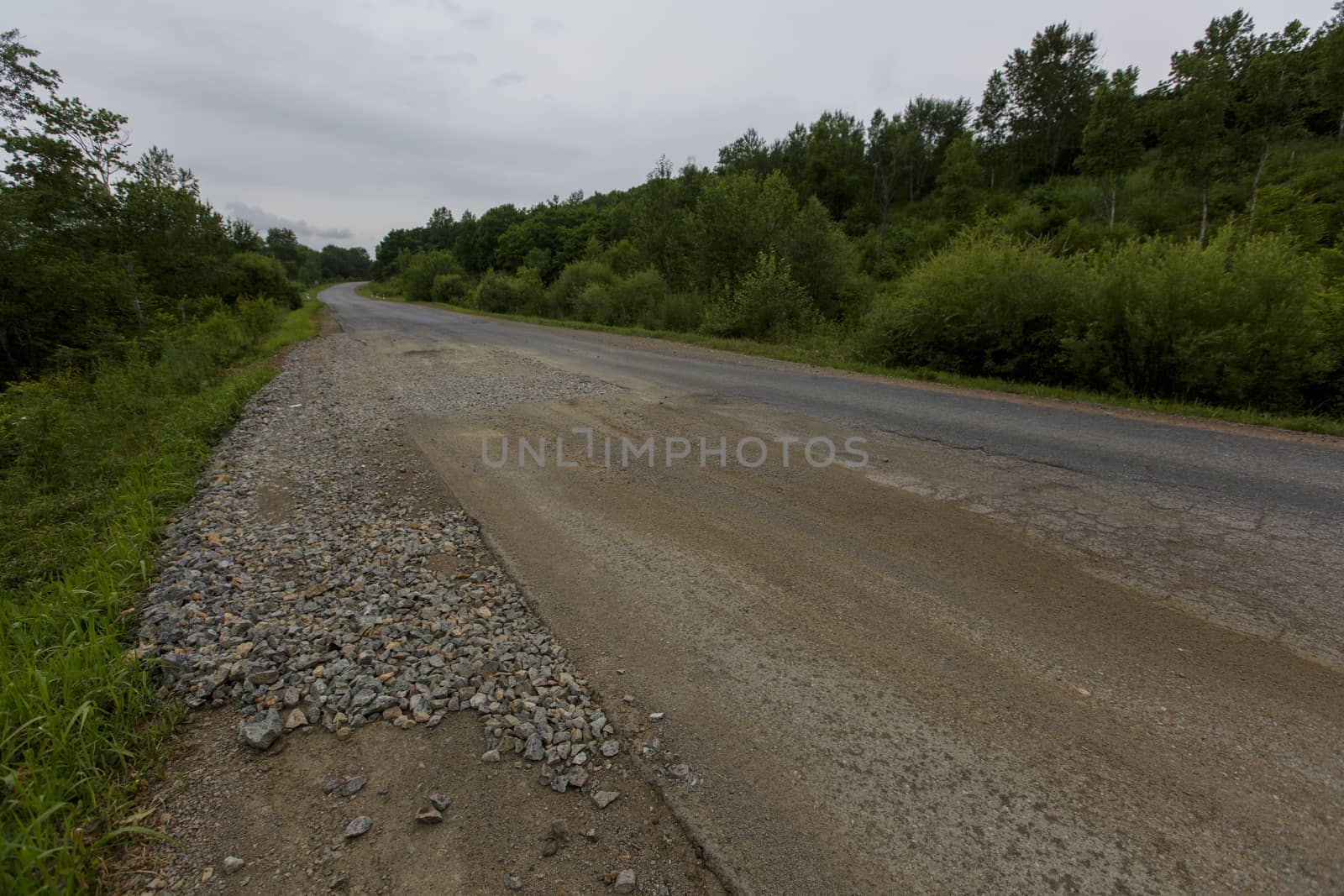 Very bad road in Russia. The asphalt road is all in holes in the middle of the forest