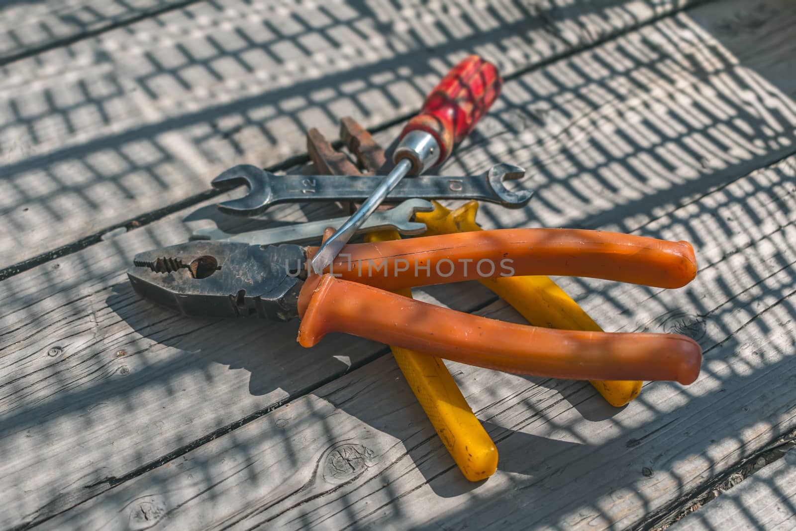 Heap of working tools, pliers, screwdrivers and wrenches on a wooden table