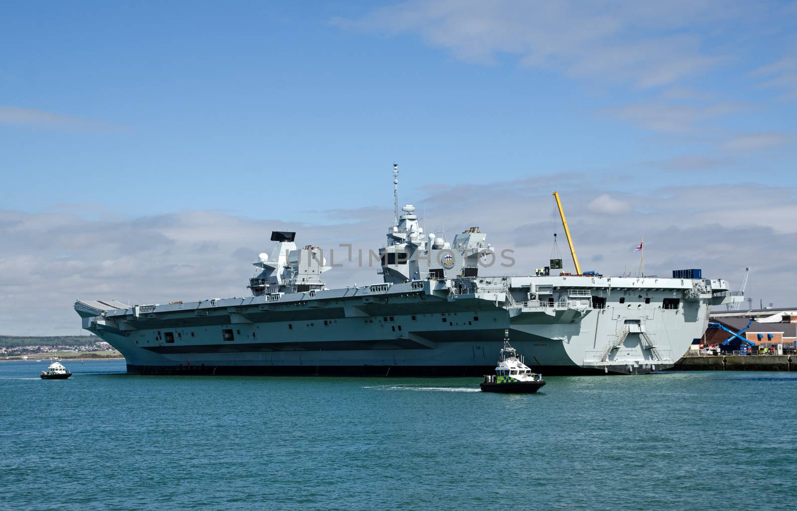 View of the Royal Navy aircraft carrier HMS Prince of Wales being fitted out in Portsmouth Harbour, Hampshire on a sunny day.