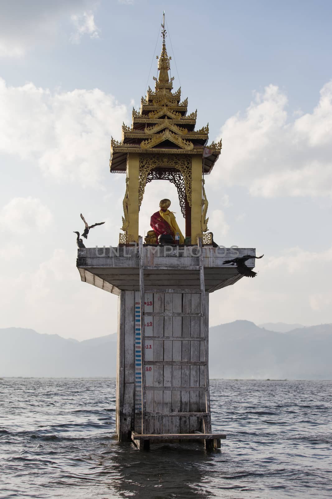 Fishermen's Buddhist shrine water level marker Inle Lake Myanmar . High quality photo