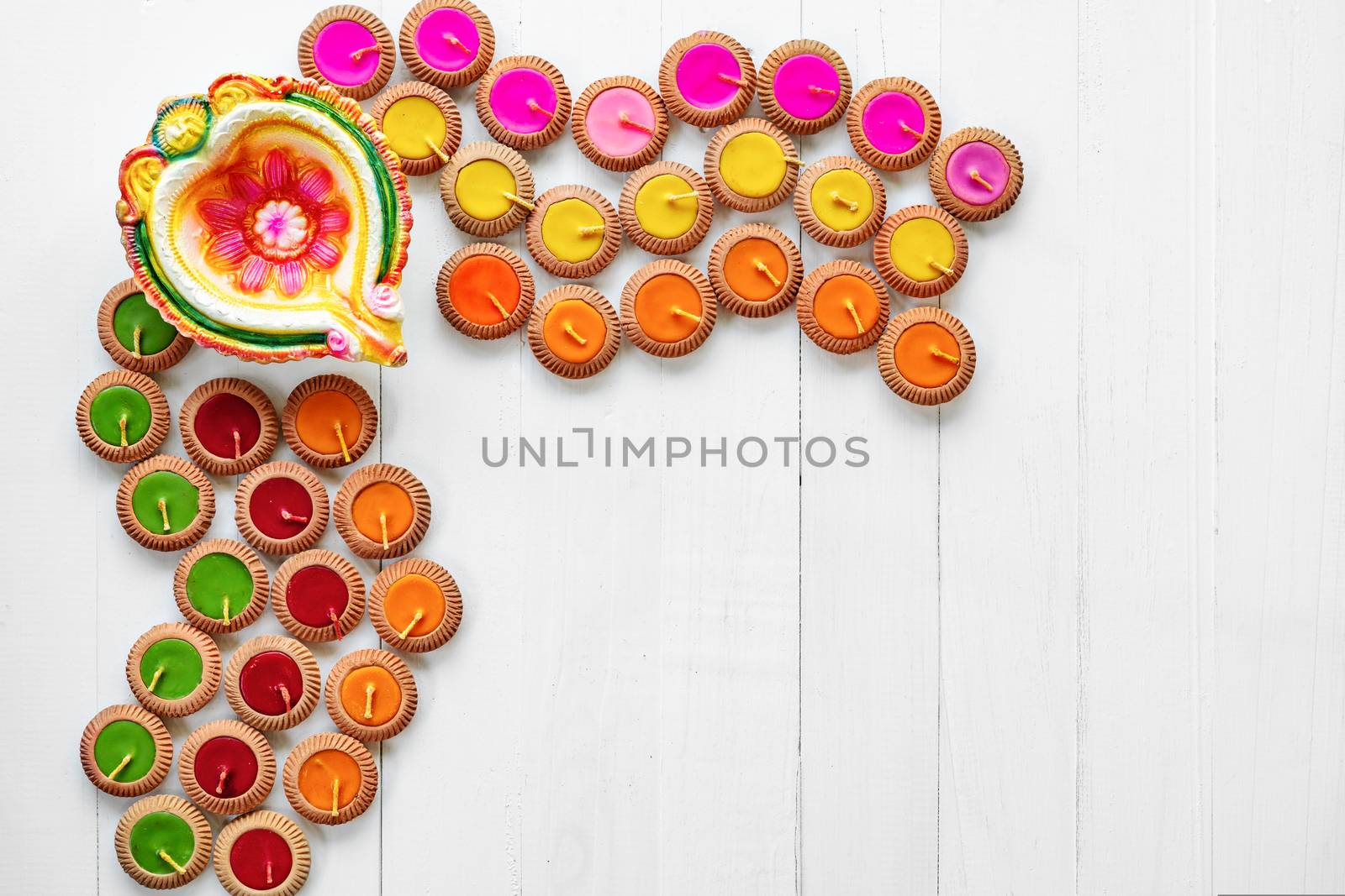 Happy Diwali - Clay Diya lamps lit during Dipavali, Hindu festival of lights celebration. Colorful traditional oil lamp diya on white wooden background