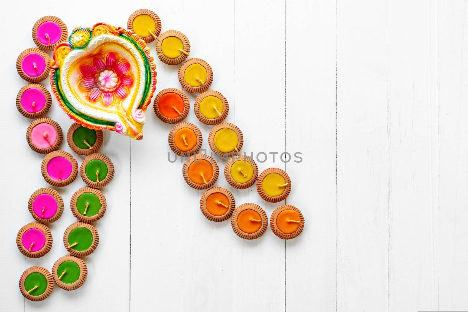 Happy Diwali - Clay Diya lamps lit during Dipavali, Hindu festival of lights celebration. Colorful traditional oil lamp diya on white wooden background