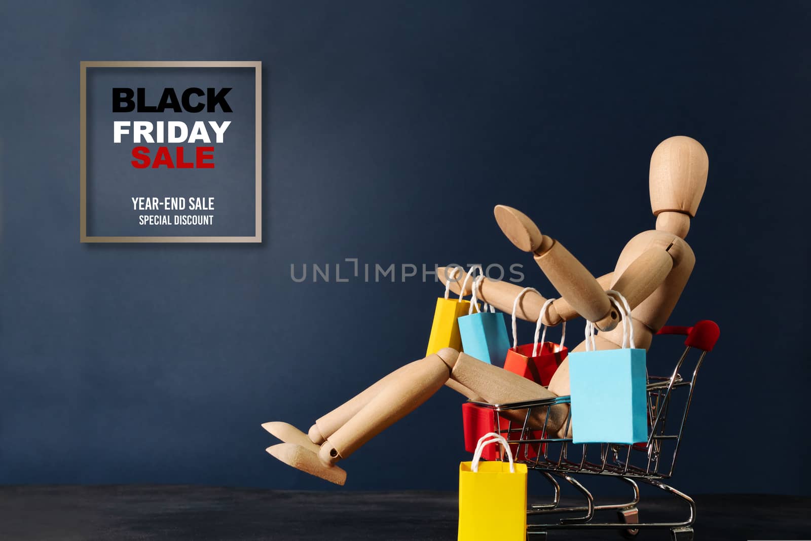Black Friday sale, wooden doll sitting on shopping cart with shopping bag