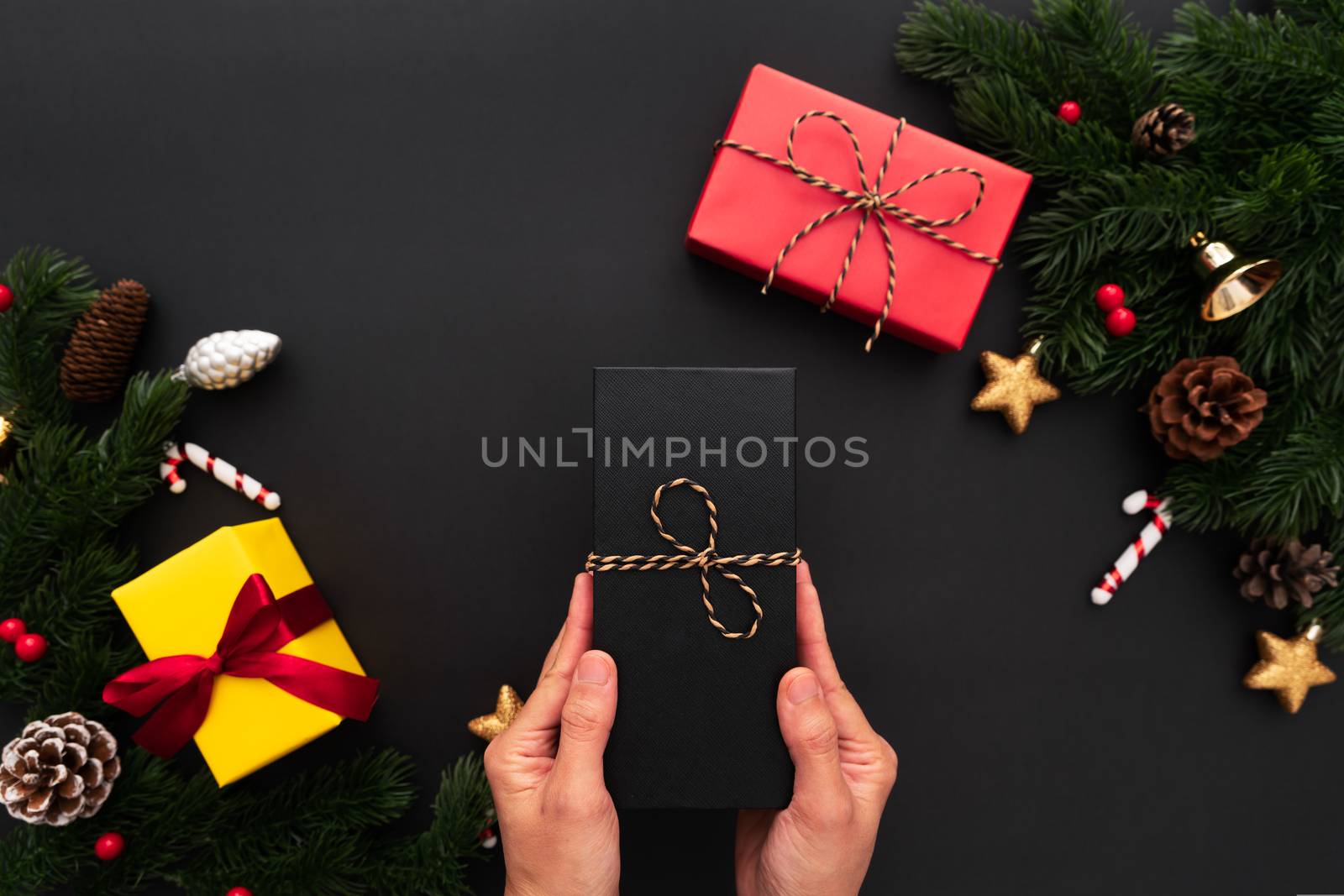 Hand hold christmas gift box with pine tree and xmas decoration on black background