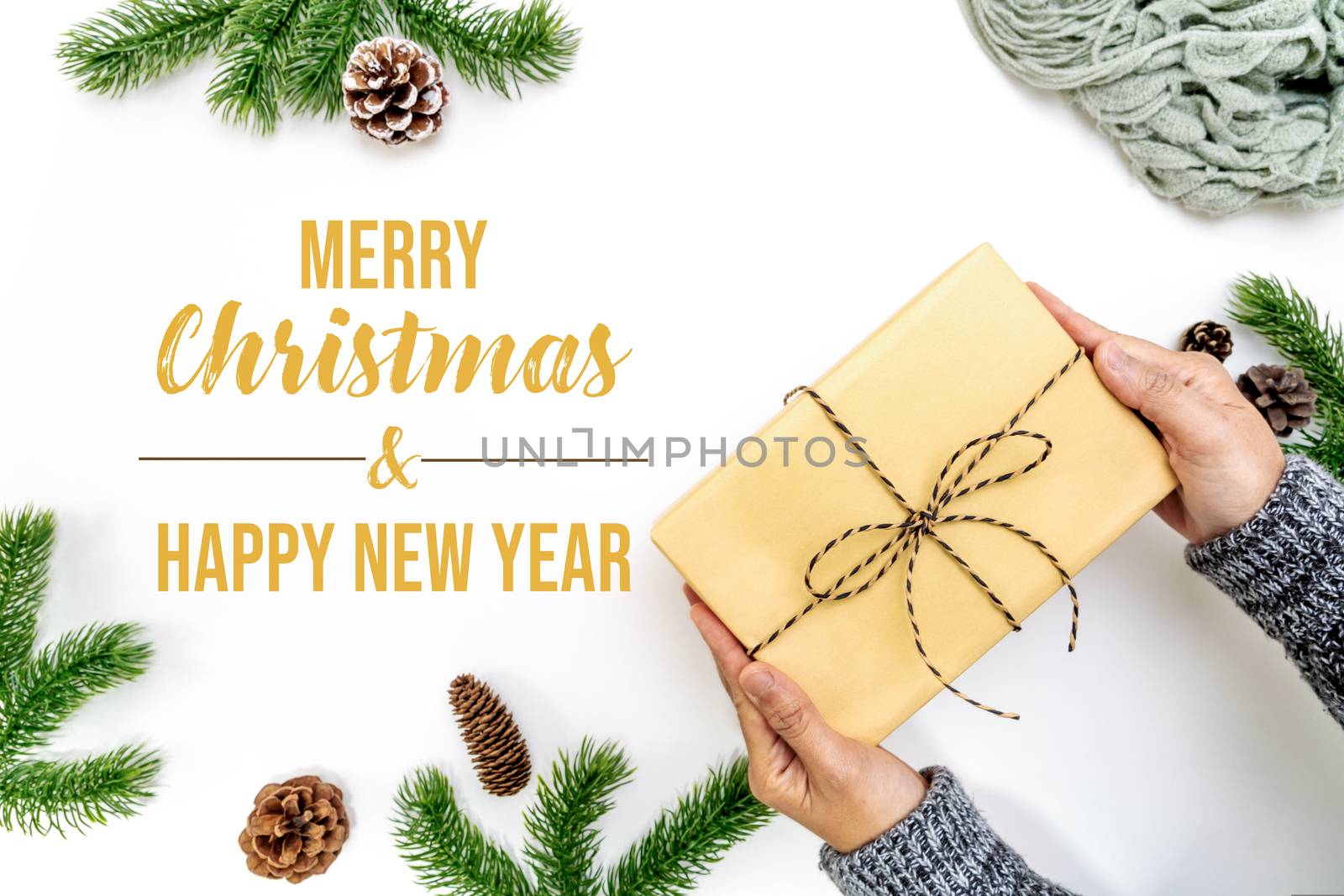 Christmas winter composition. Woman hand hold christmas gift box with pine cones, fir branches on white background. Flat lay, top view, copy space
