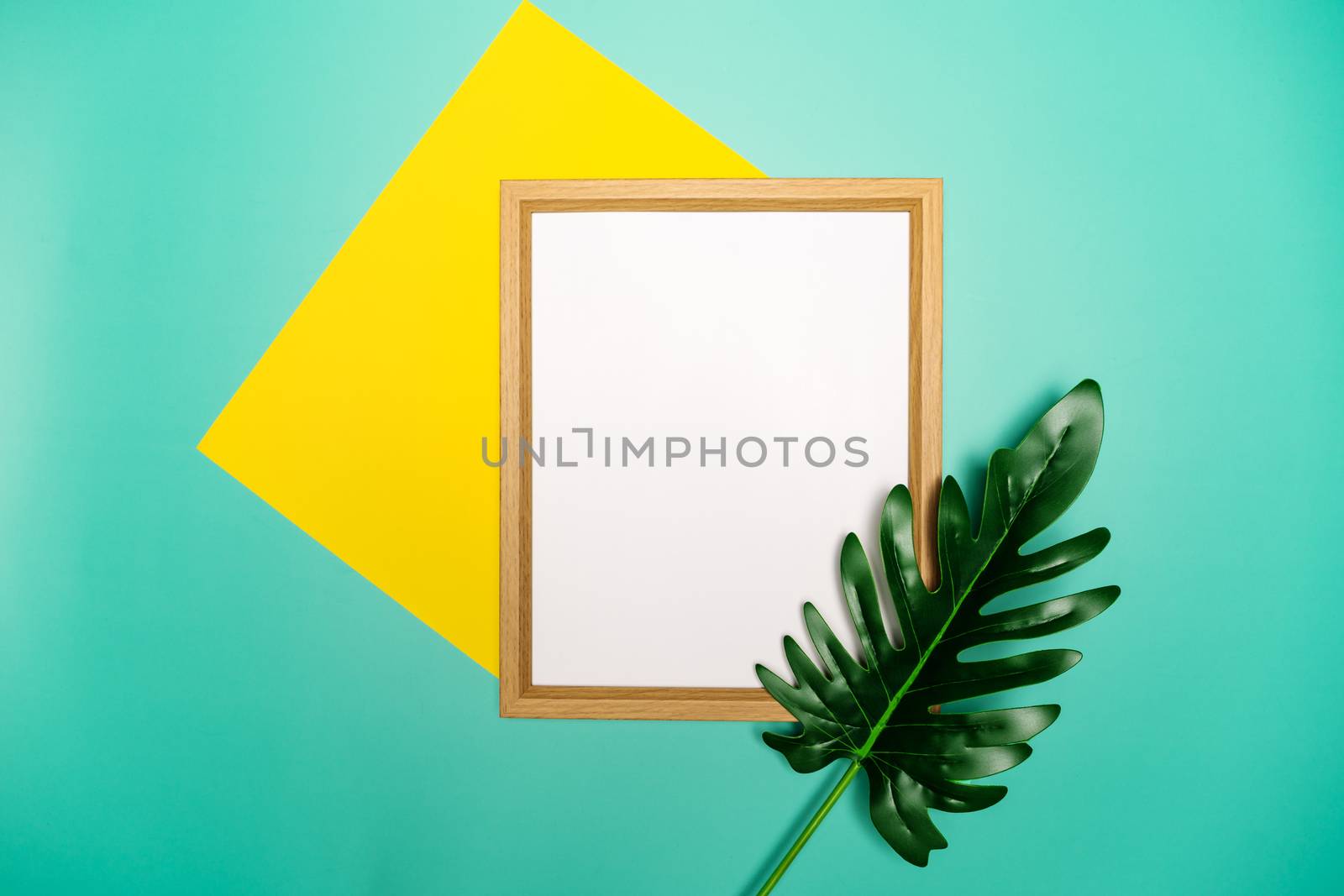 Summer composition. Tropical palm leaves, yellow paper blank, photo frame on pastel green background.