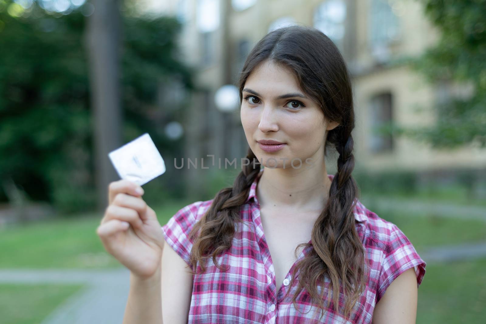 Girl holding a condom. Protected sex and health by Mykola_Kondrashev