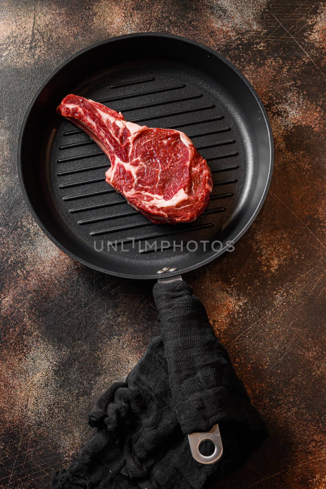 Cowboy steak on the grill pan or tomahawk steak raw top view. ove rustic metal dark background table.