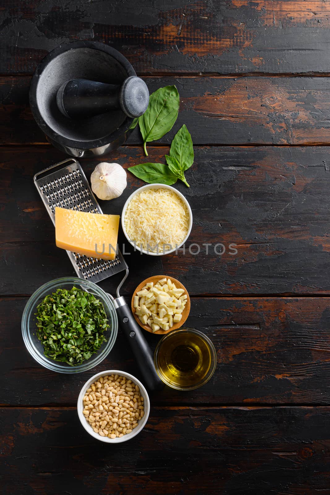 Fresh ingredients for pesto genovese Italian food cooking ingredients on dark background with rustic wooden chopping board, top view, vertical copy space on side by Ilianesolenyi