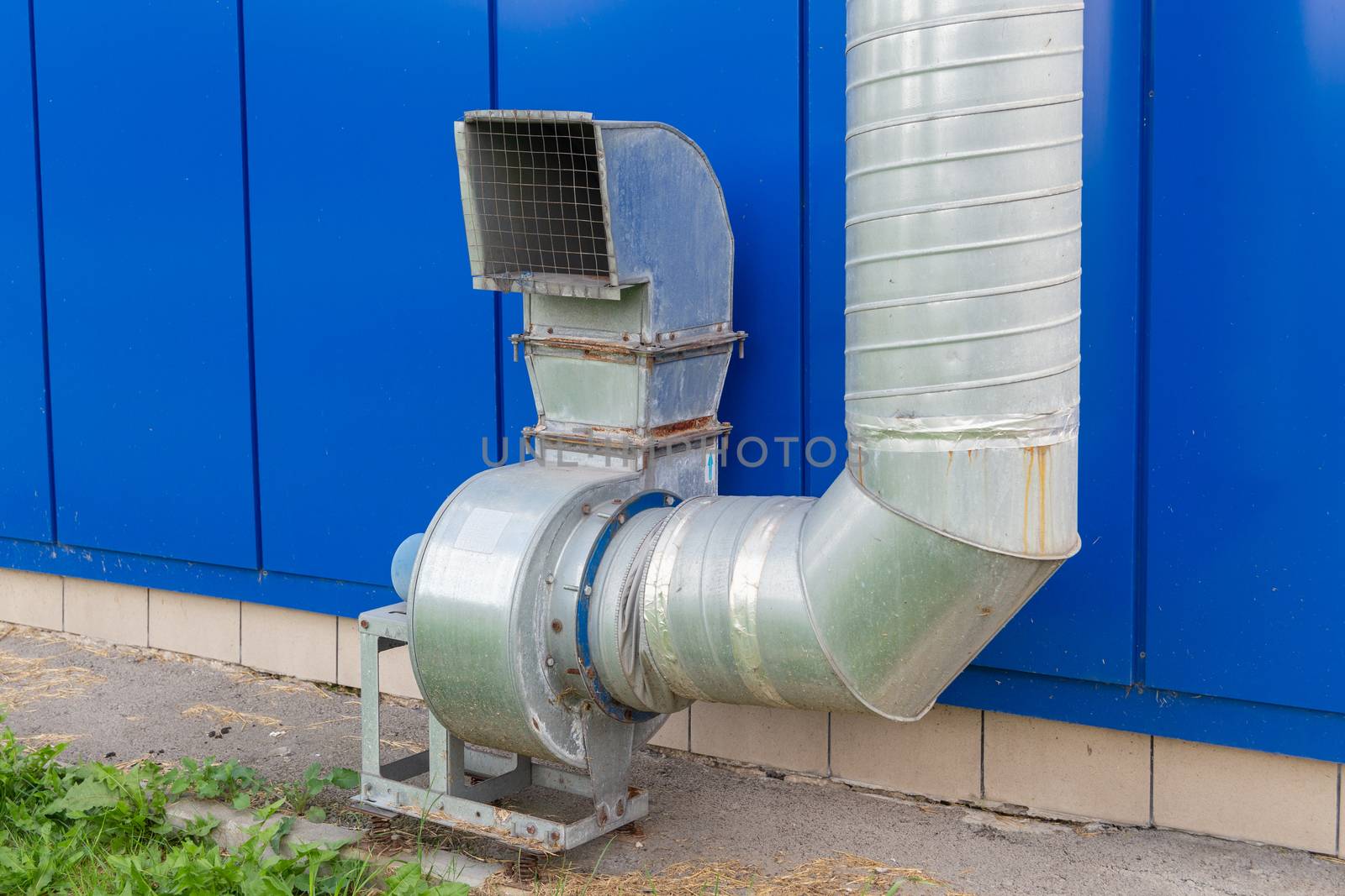 industrial grade air extraction duct with electrical motor on blue wall.