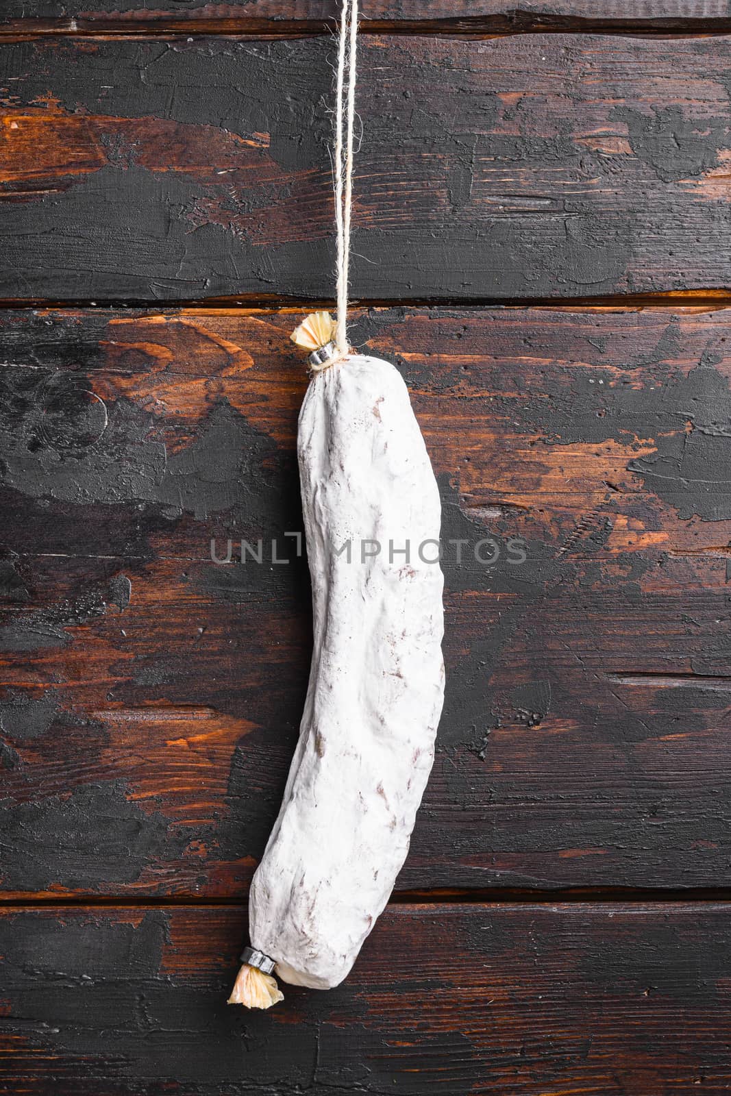 Dry cured salchichon spanish wurst on dark wood background.