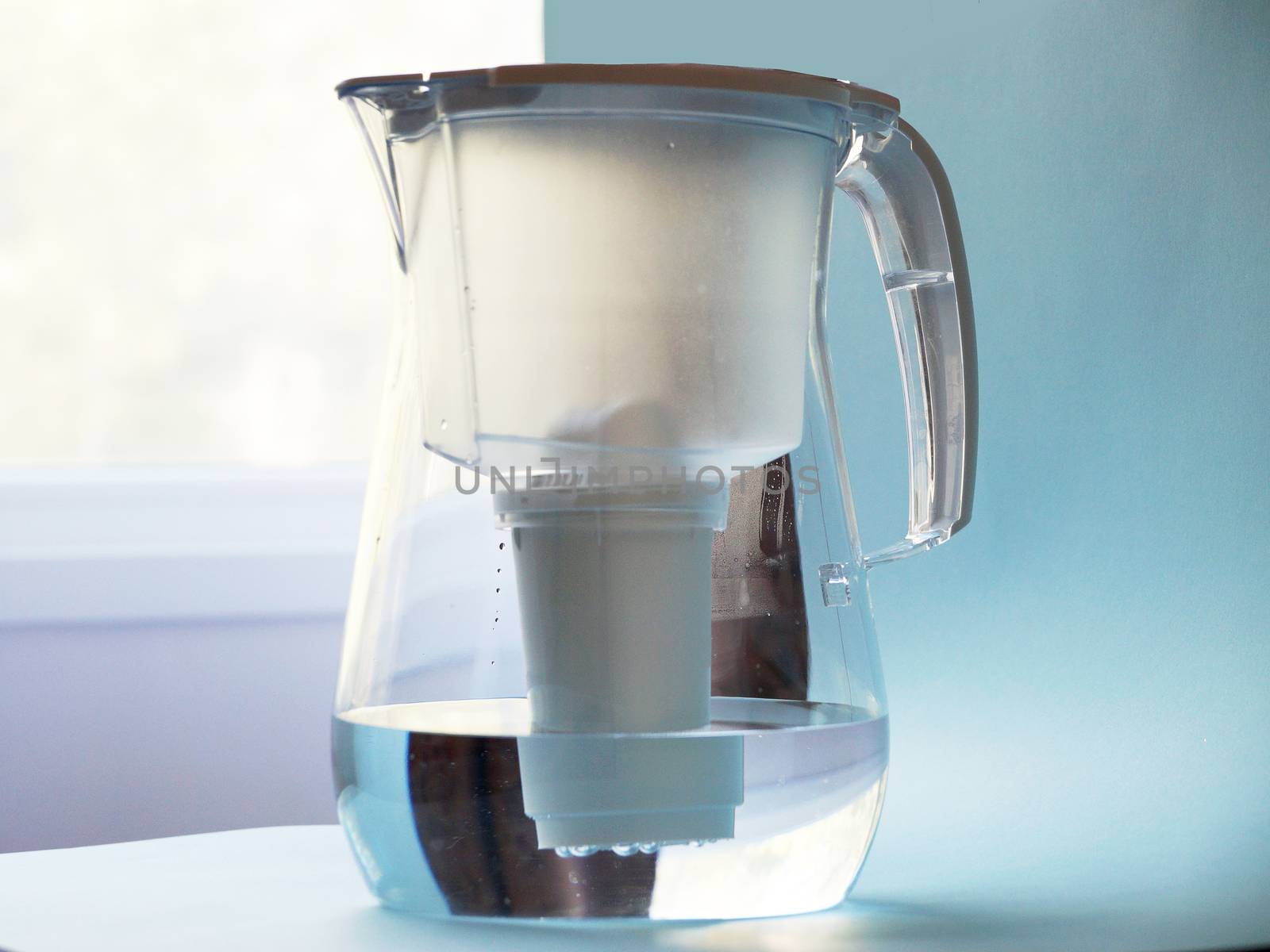 a jug for filtering water against the background of the window. by Annado