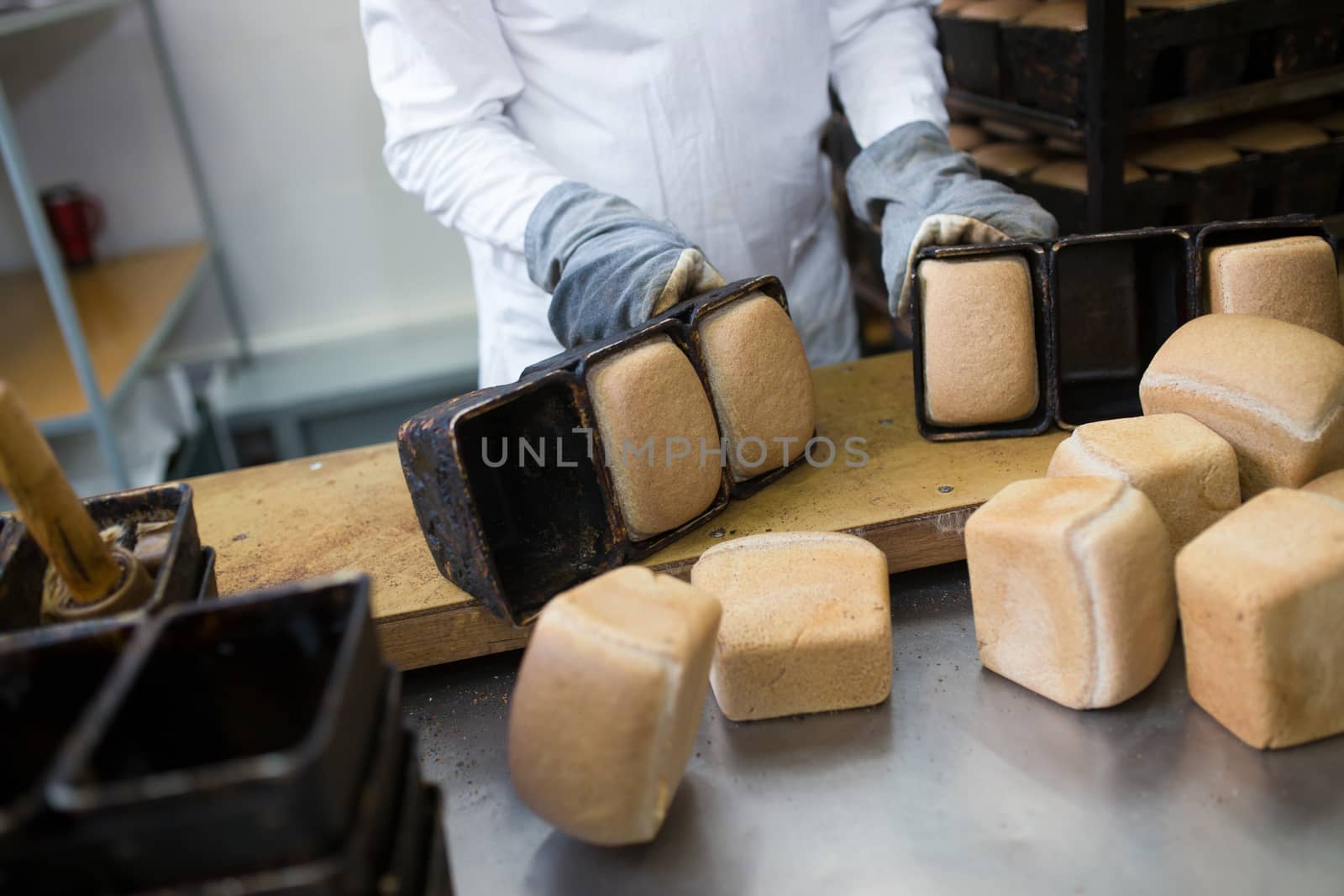 Close-up. Baker dumps freshly prepared bread out of molds on the table.