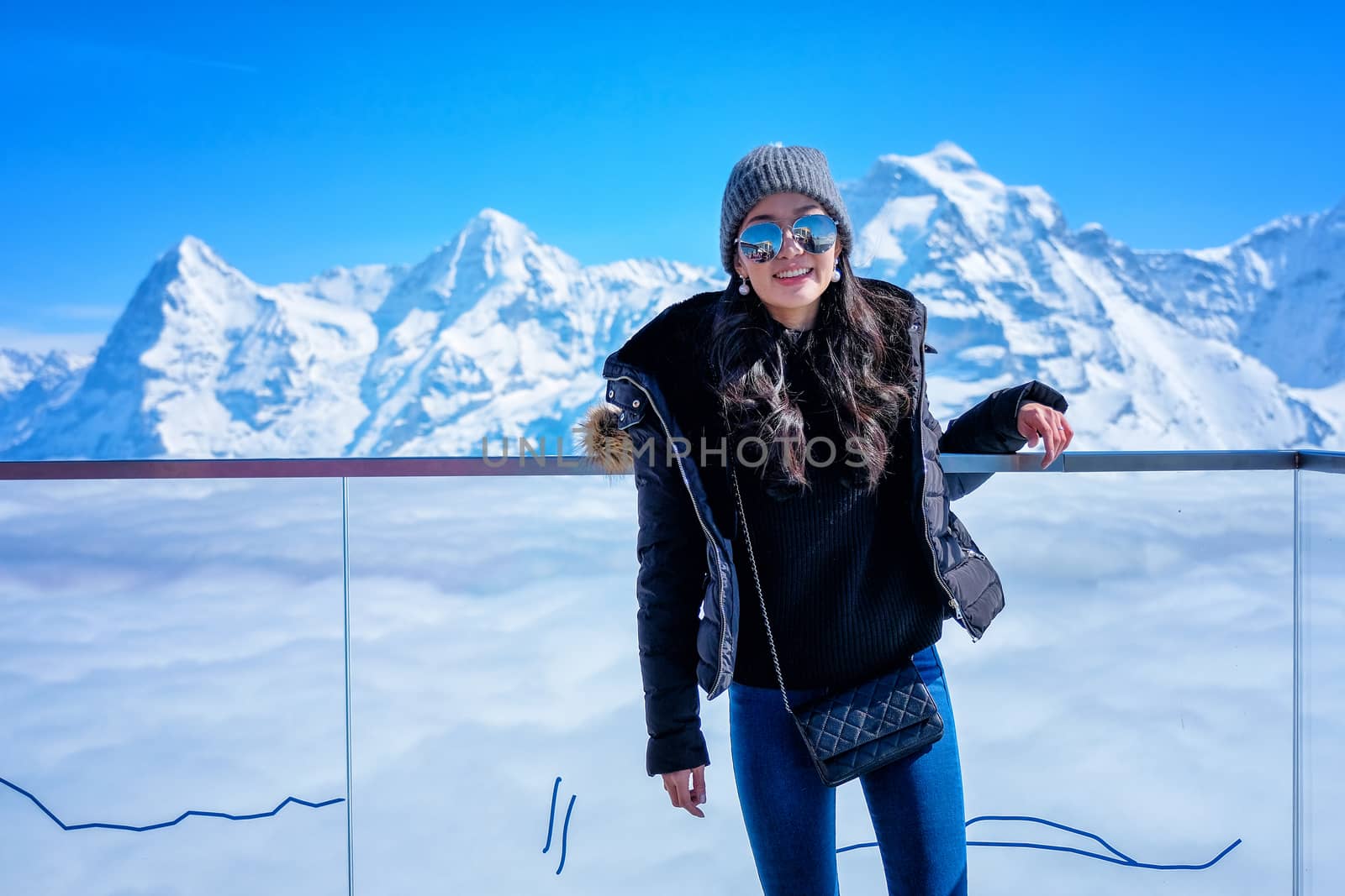 Young Woman Tourist at the Schilthorn in Switzerland with a magnificent panoramic view of the Swiss Skyline. 