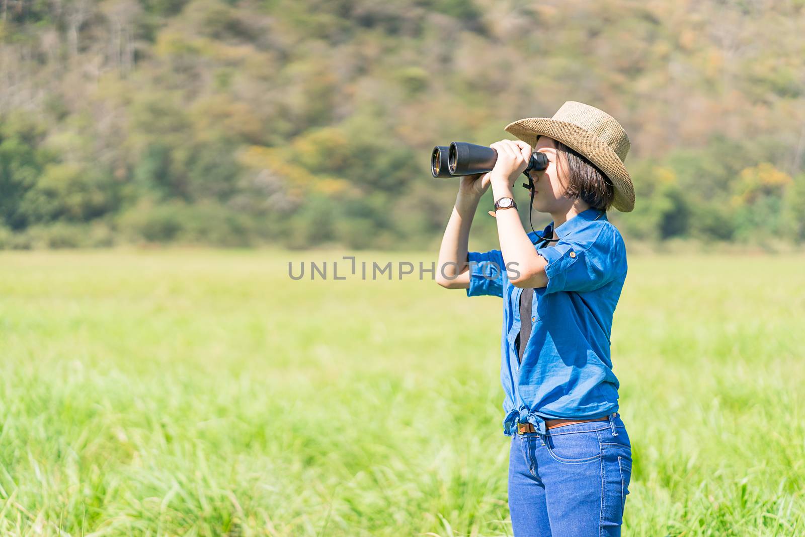 Woman wear hat and hold binocular in grass field by stoonn