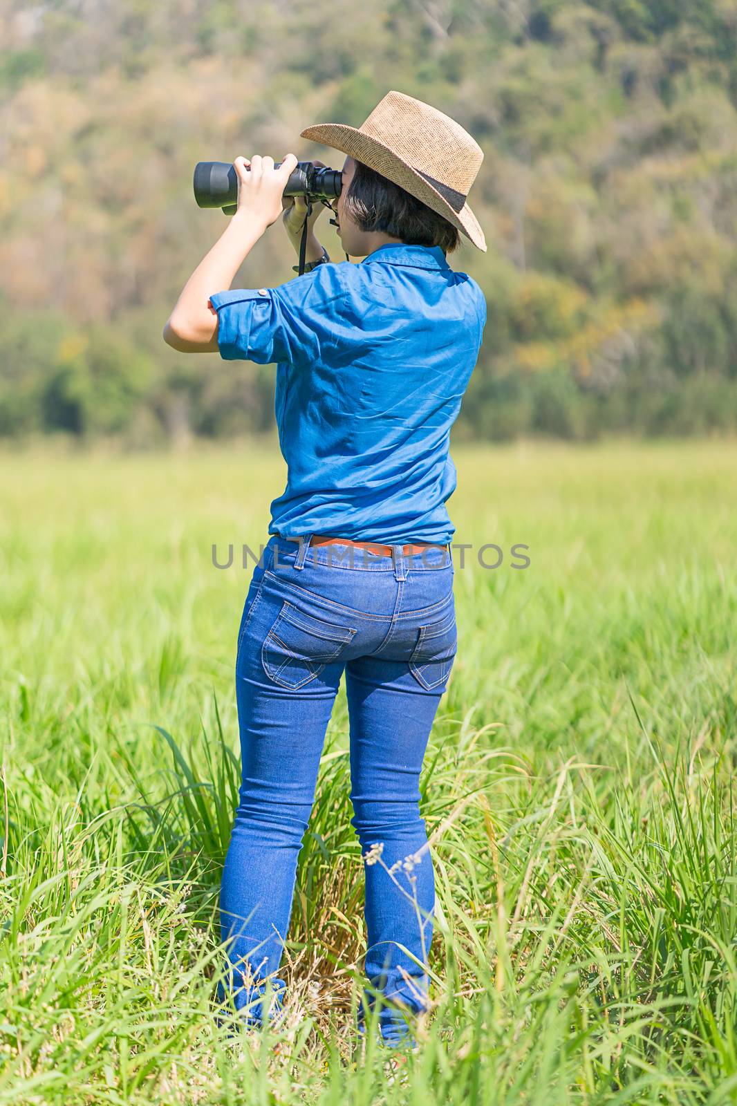 Woman wear hat and hold binocular in grass field by stoonn