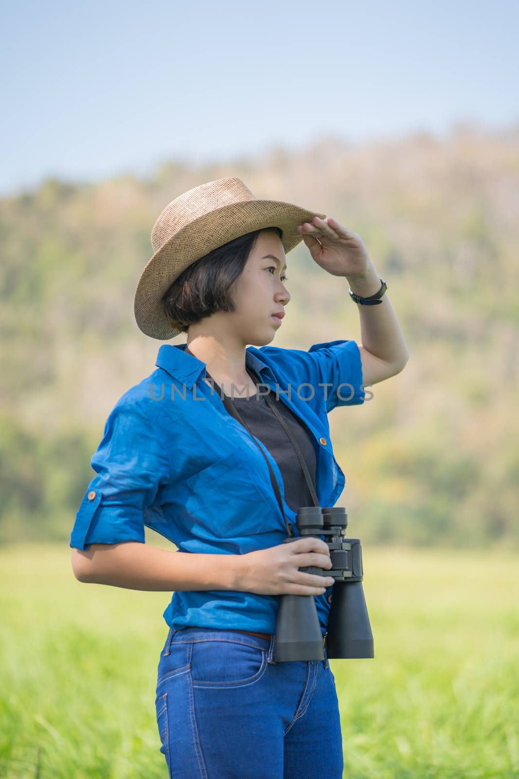 Woman wear hat and hold binocular in grass field by stoonn