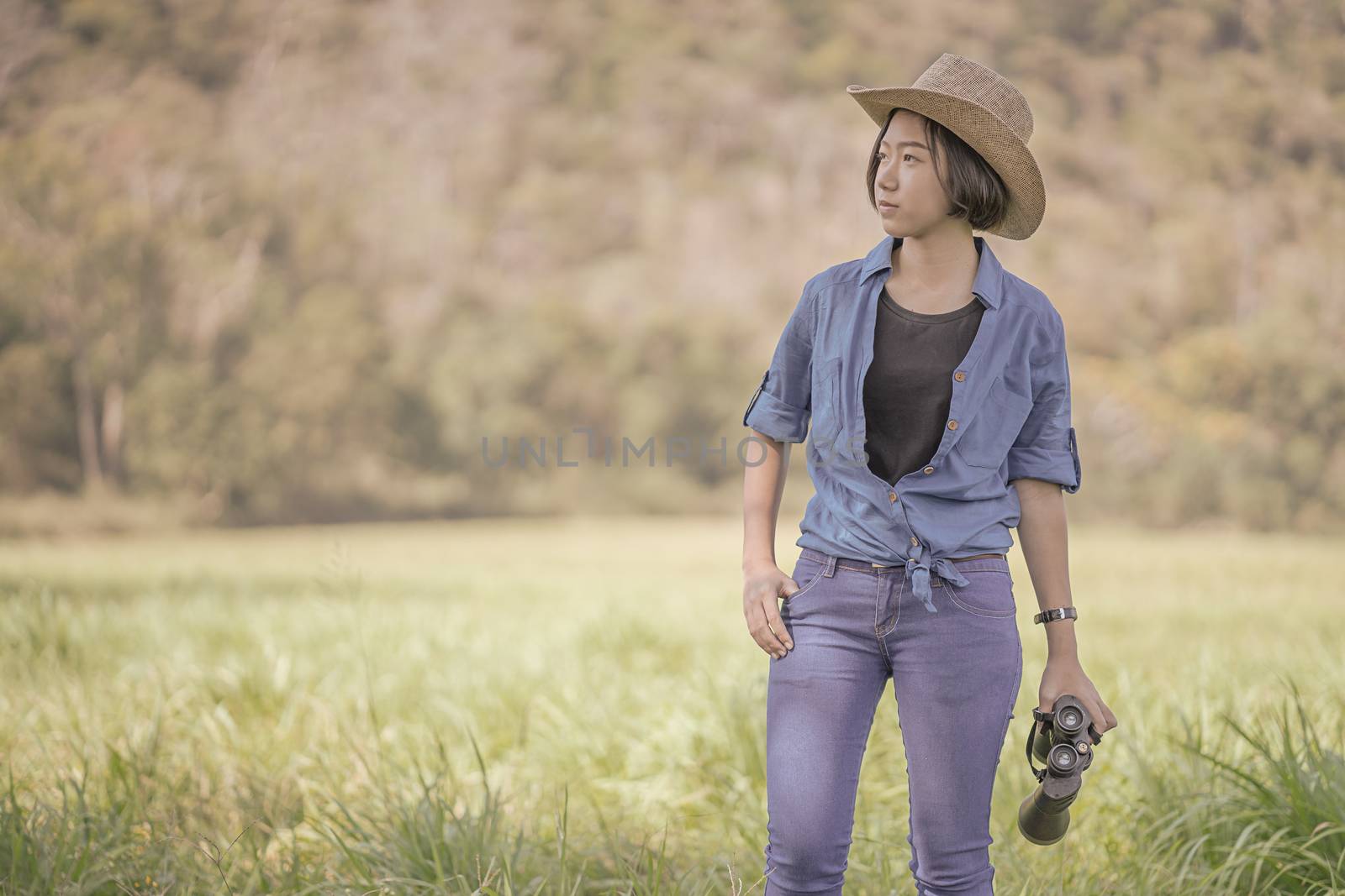 Woman wear hat and hold binocular in grass field by stoonn