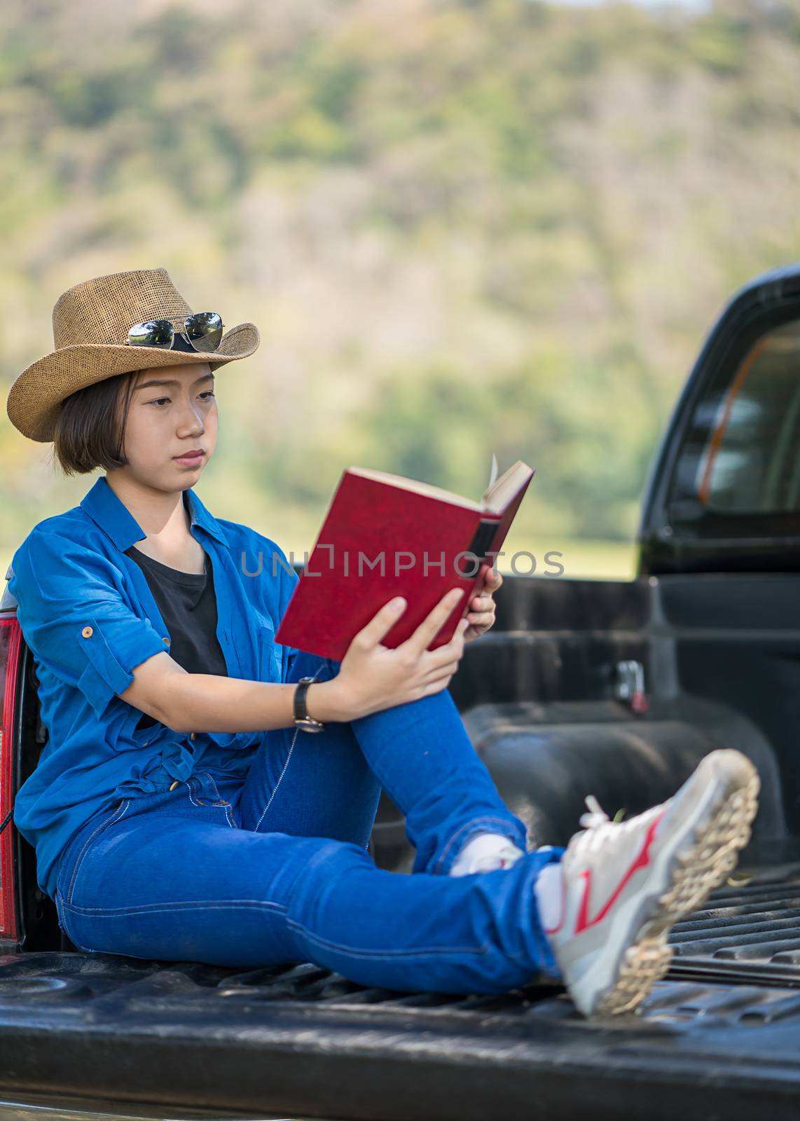 Woman wear hat and reading the book on pickup truck by stoonn