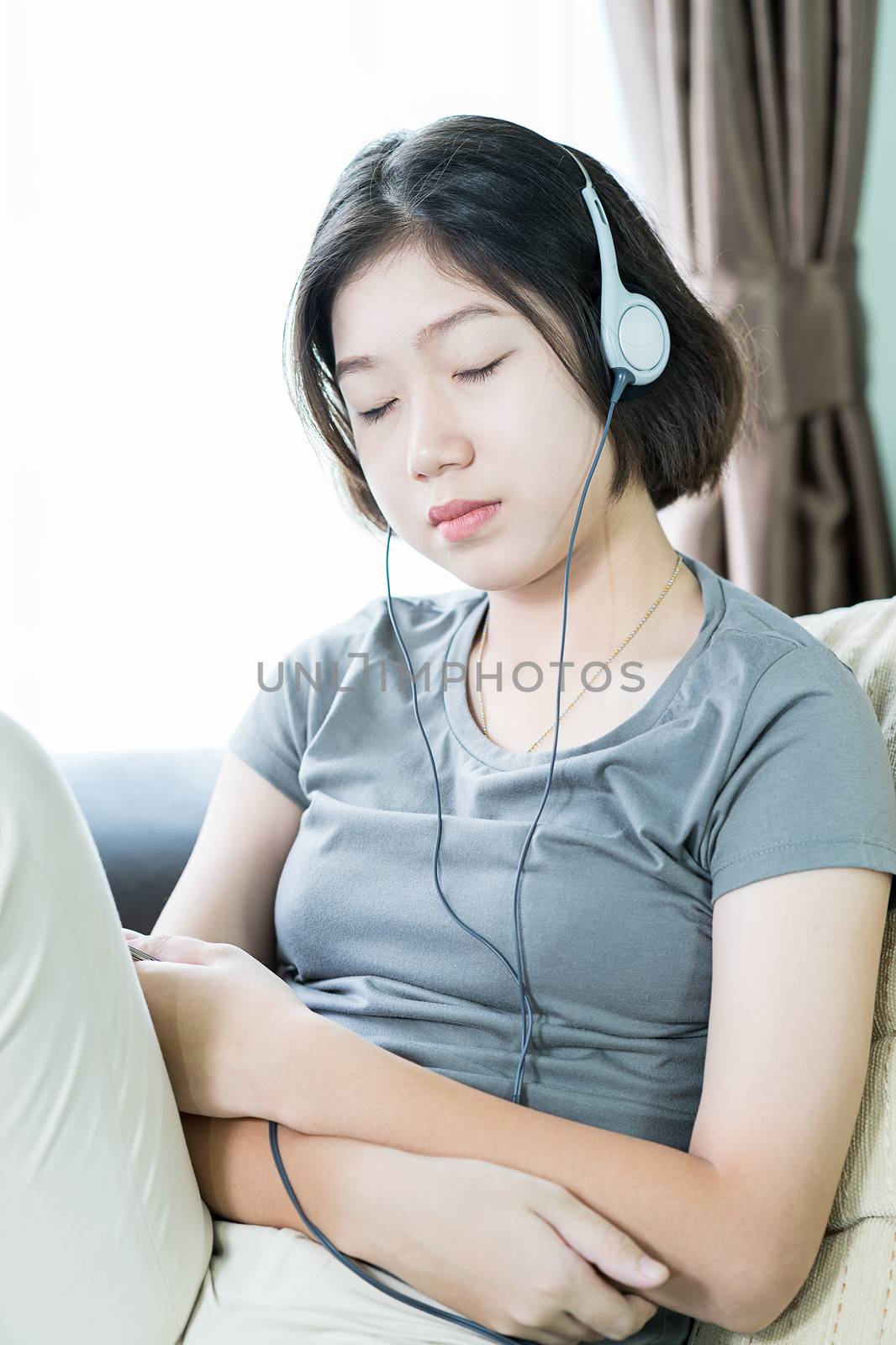 Close up young asian woman short hair listening music from mobile phone on the couch