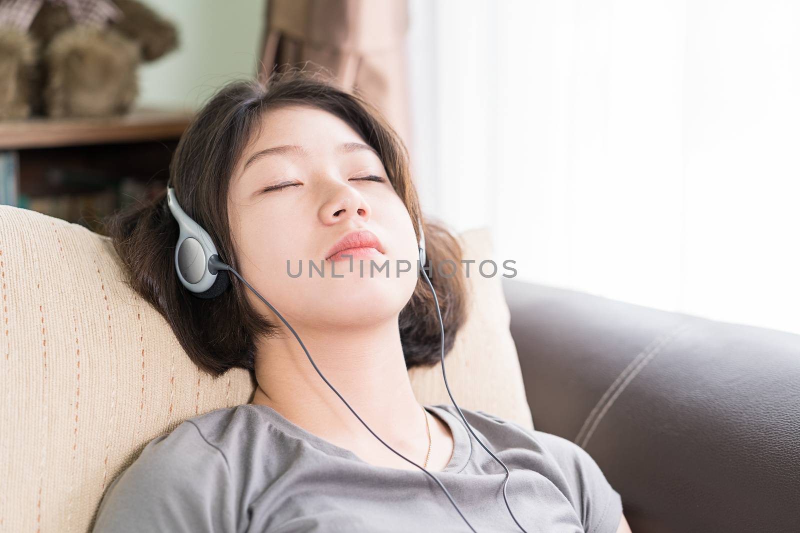 Close up young asian woman short hair listening music from mobile phone on the couch