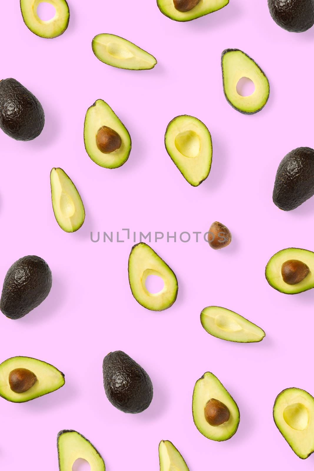 Avocado. Background made from isolated Avocado pieces on pink background. Flat lay of fresh ripe avocados and avacado pieces. by PhotoTime