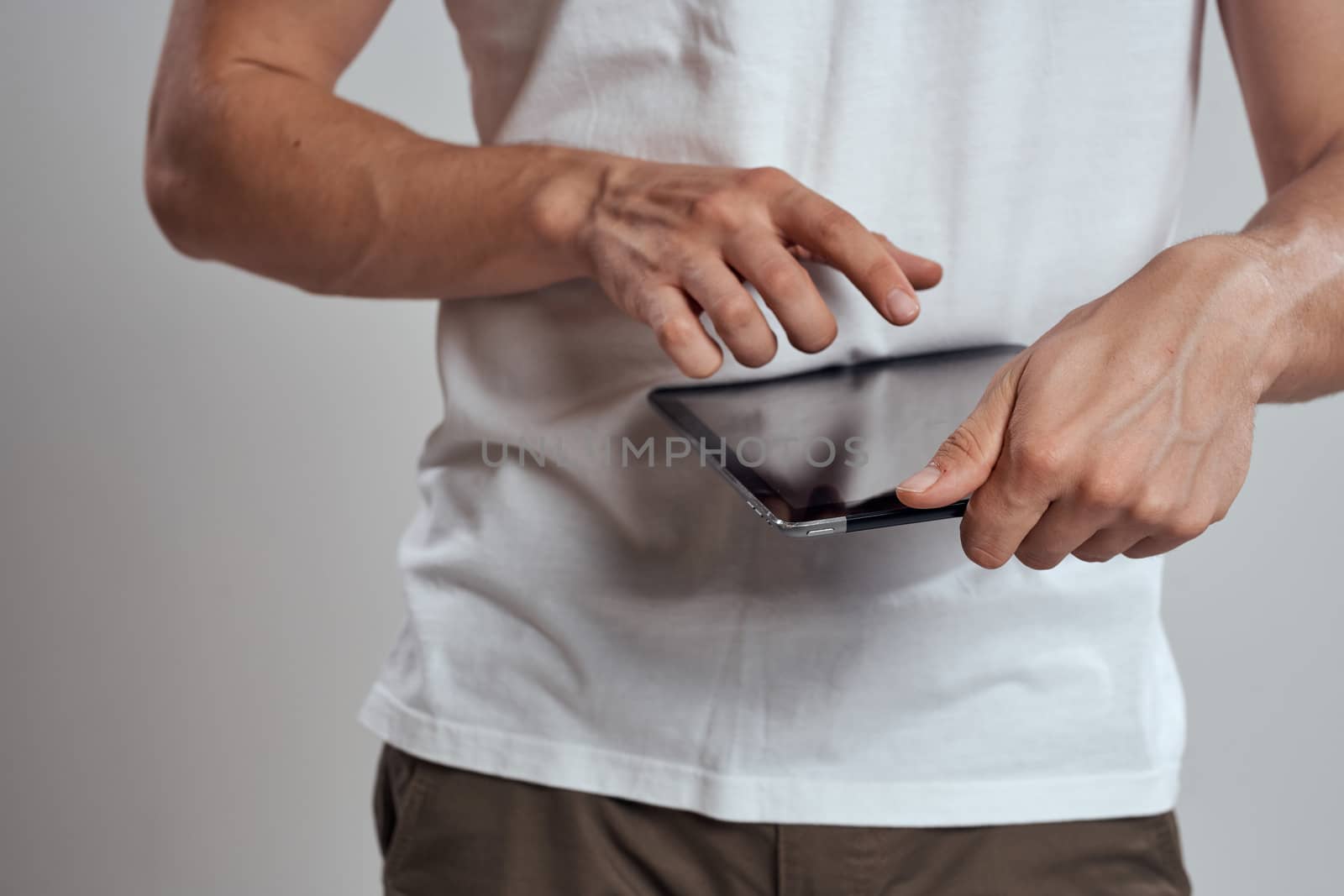 Tablet with a touch screen on a light background male hands white t-shirt cropped view by SHOTPRIME