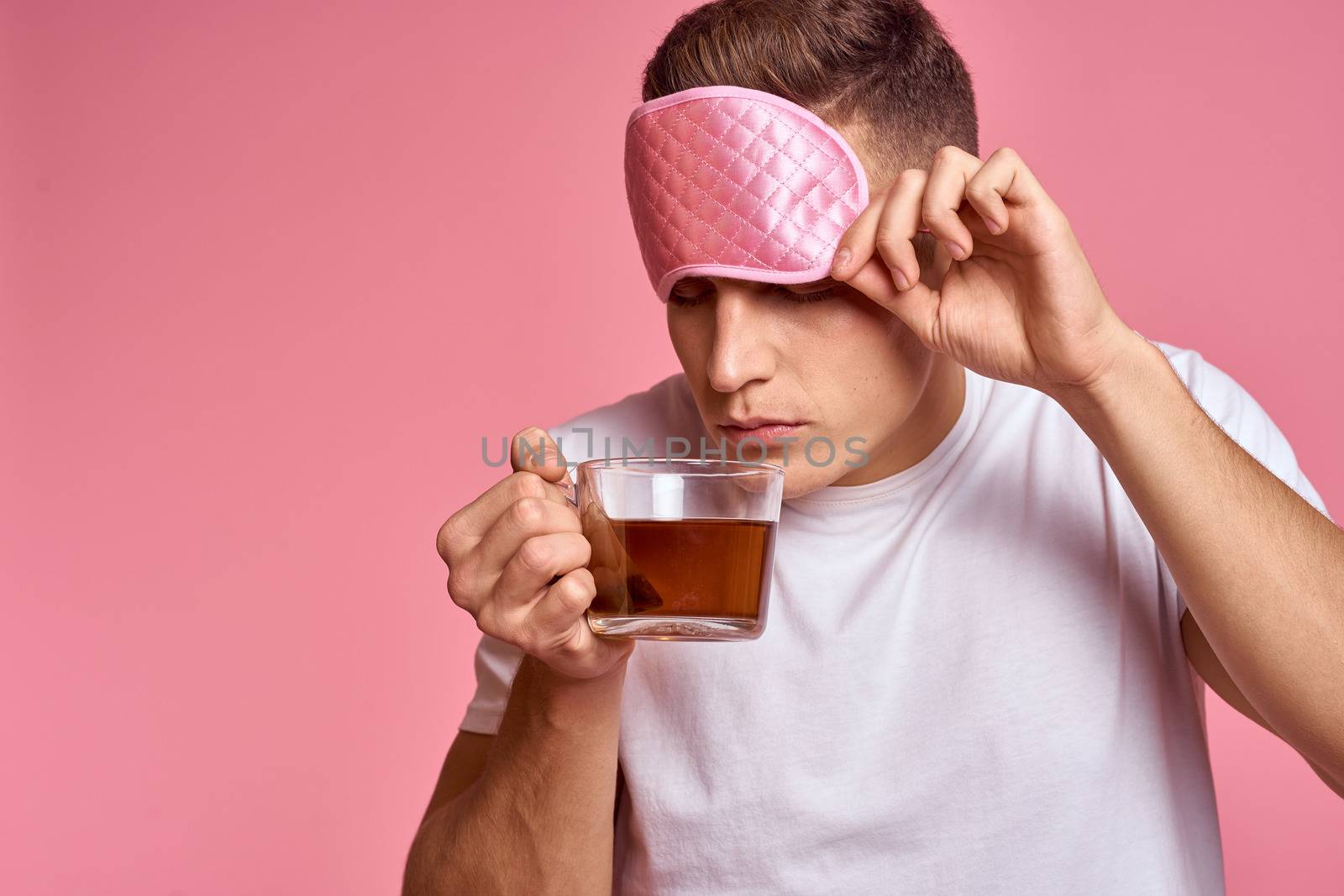 A man with a hot drink and a cup of tea pink mask for a vigorous morning sleep. High quality photo