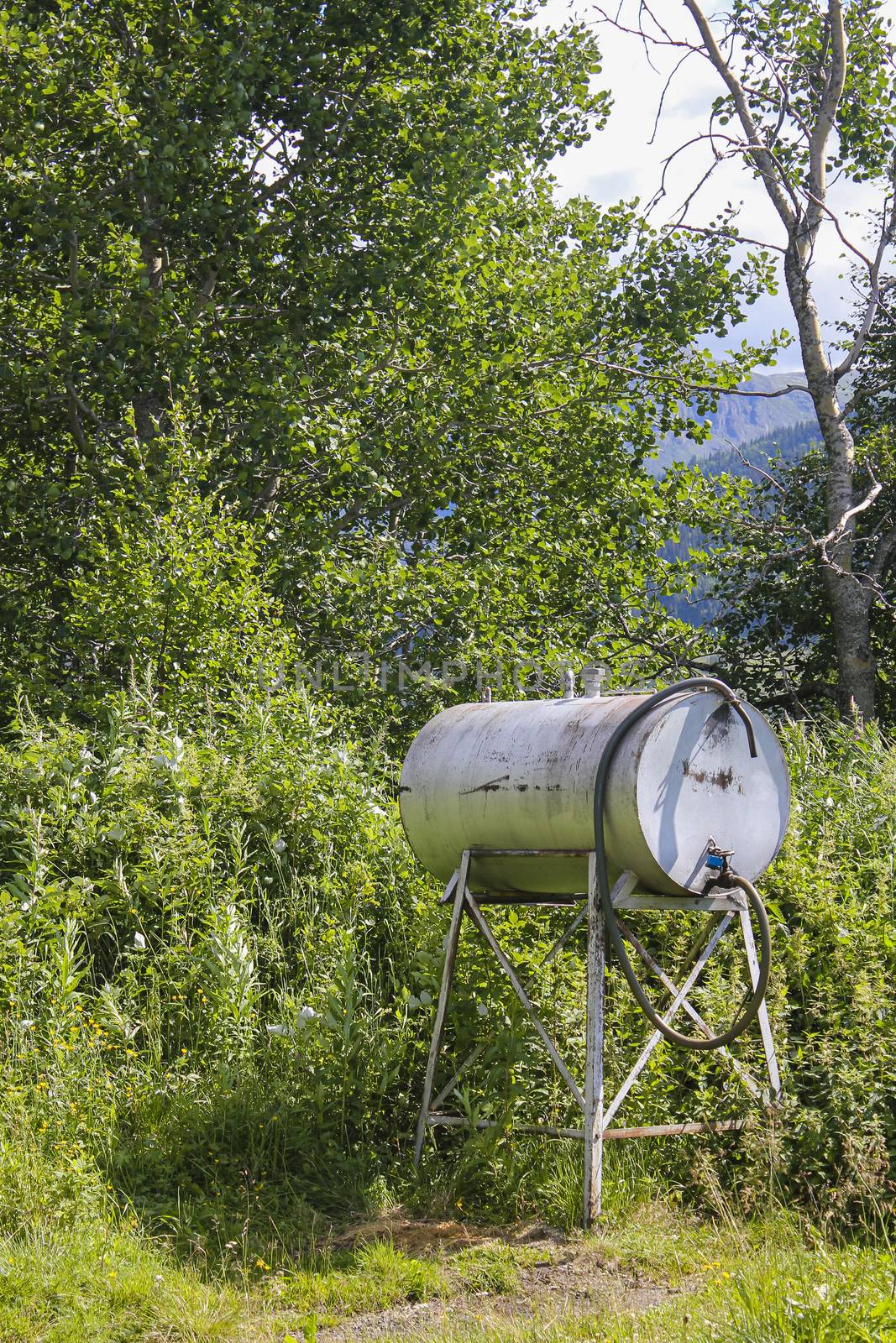 Petrol tank or water dispenser in the meadow in Norway. by Arkadij