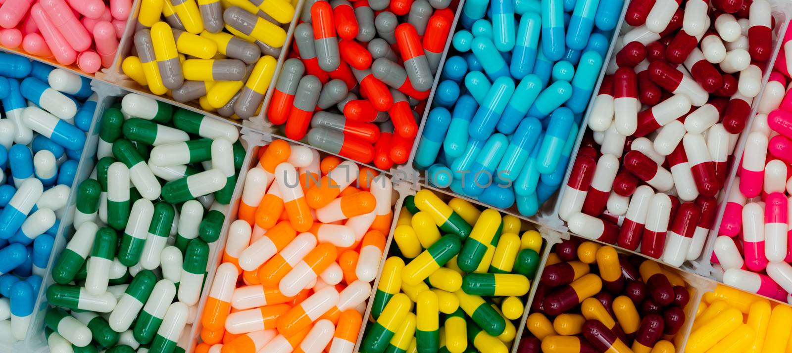 Top view of colorful capsule pills in  plastic box. Antibiotic d by Fahroni