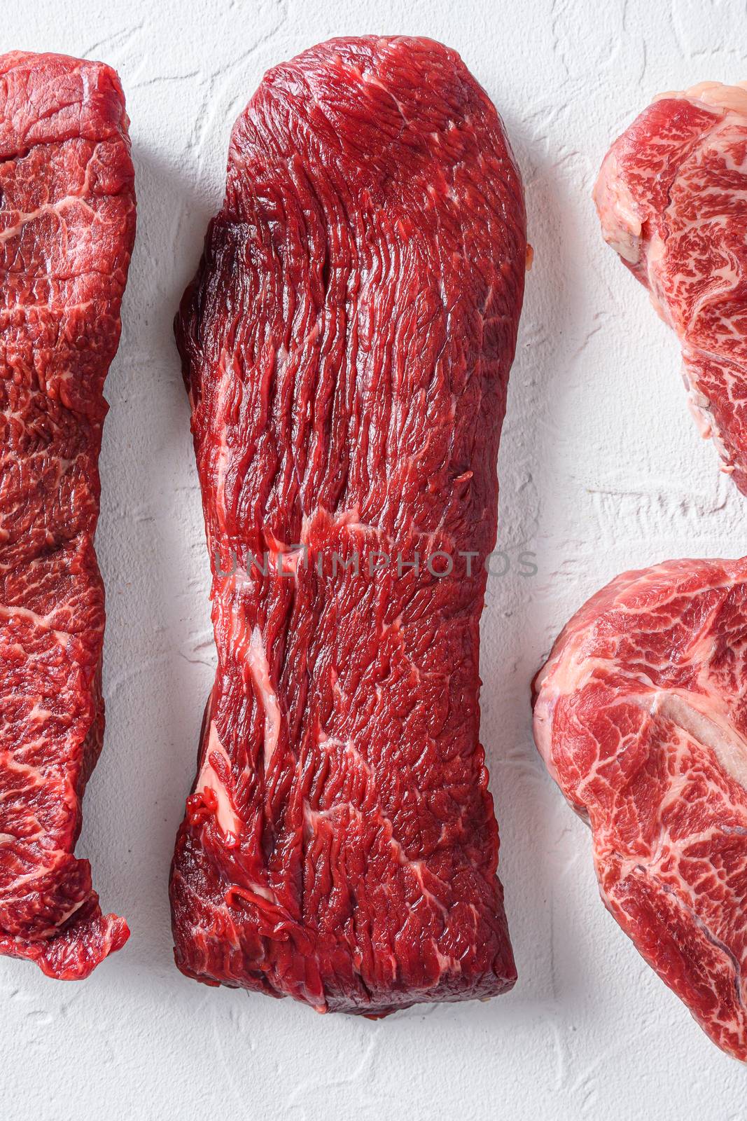 Raw tri-tip steak for BBQ cut organic meat cut top view close up over white concrete background vertical