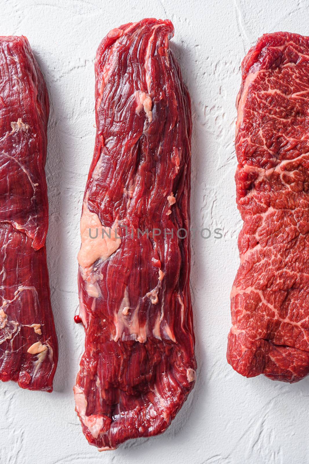 Raw machete steak for BBQ cut organic meat cut top view close up over white concrete background vertical. by Ilianesolenyi