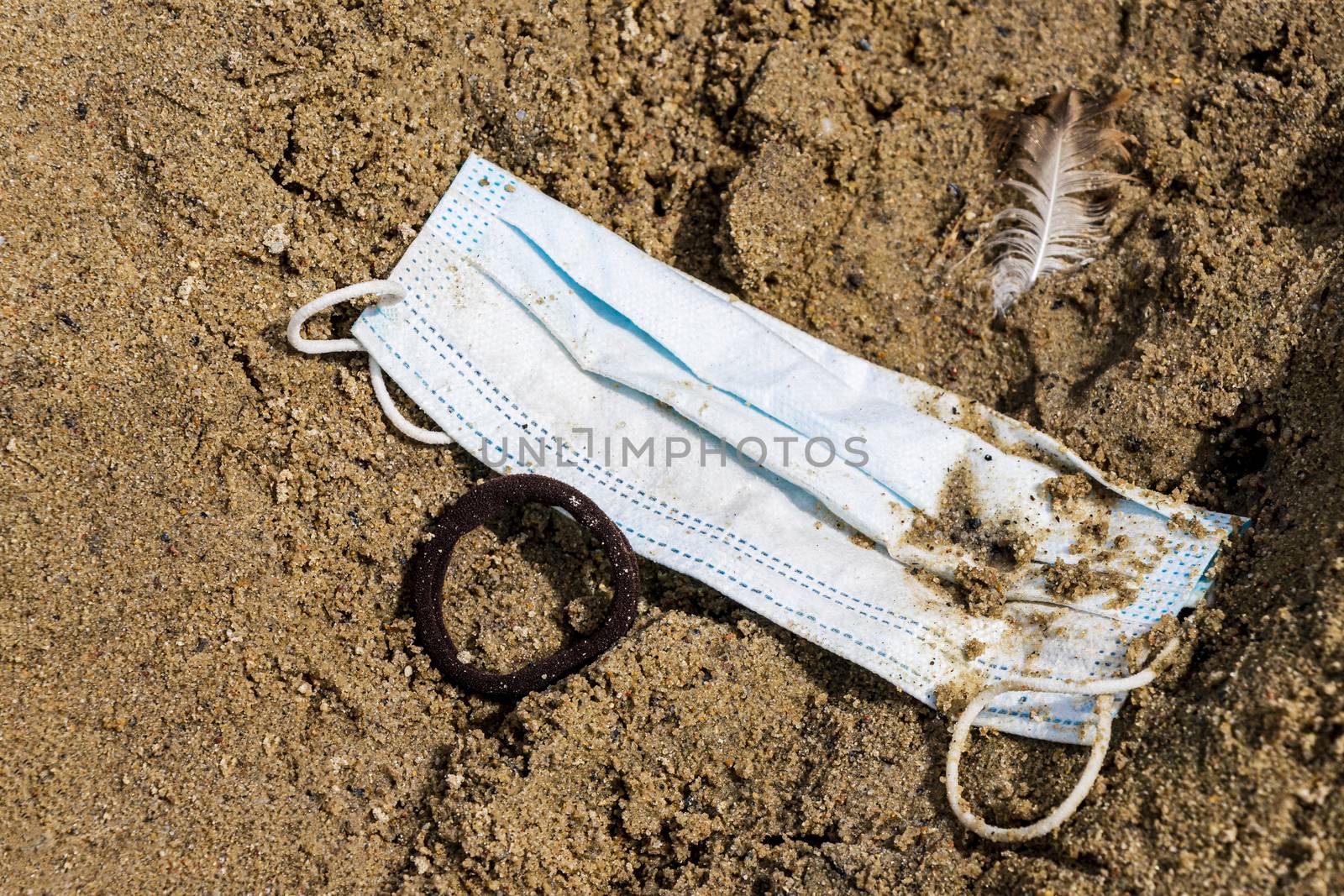 Dirty trash surgical masks on beach sand. Corona virus pollution. by Arkadij