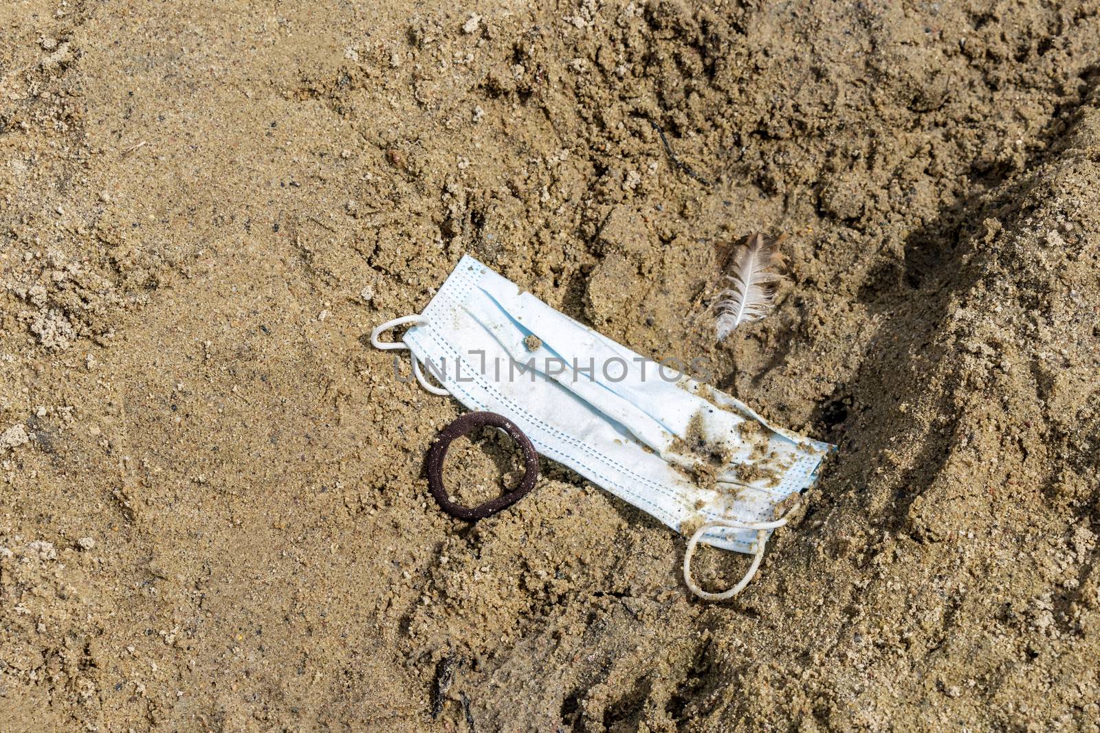 Dirty trash surgical masks on beach sand. Corona virus pollution. by Arkadij
