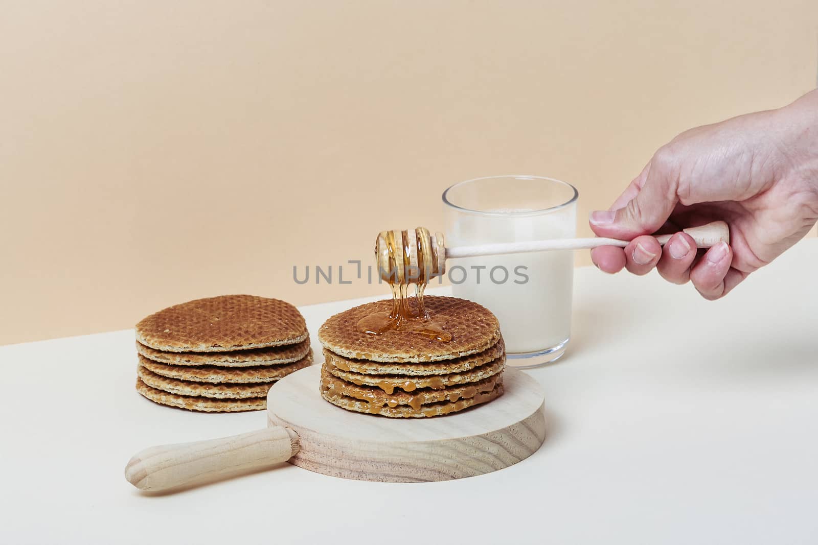 Female hand pouring honey over a pile of waffles. Copy space.